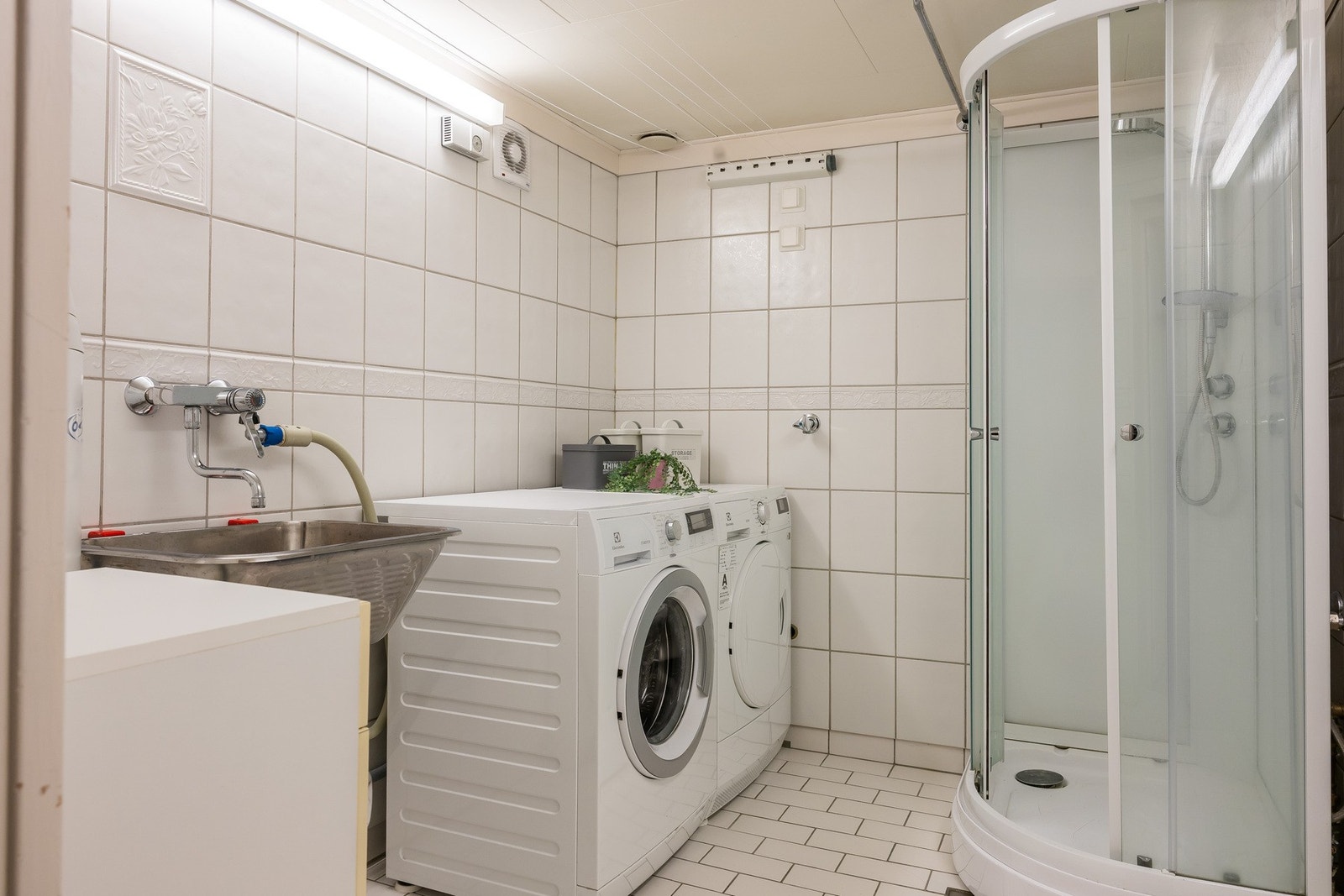 Separat vaskerom i kjeller med flislagt gulv, gulvvarme, utslagsvask, dusjkabinett, opplegg for vaskemaskin og tørketrommel. Galleribilde