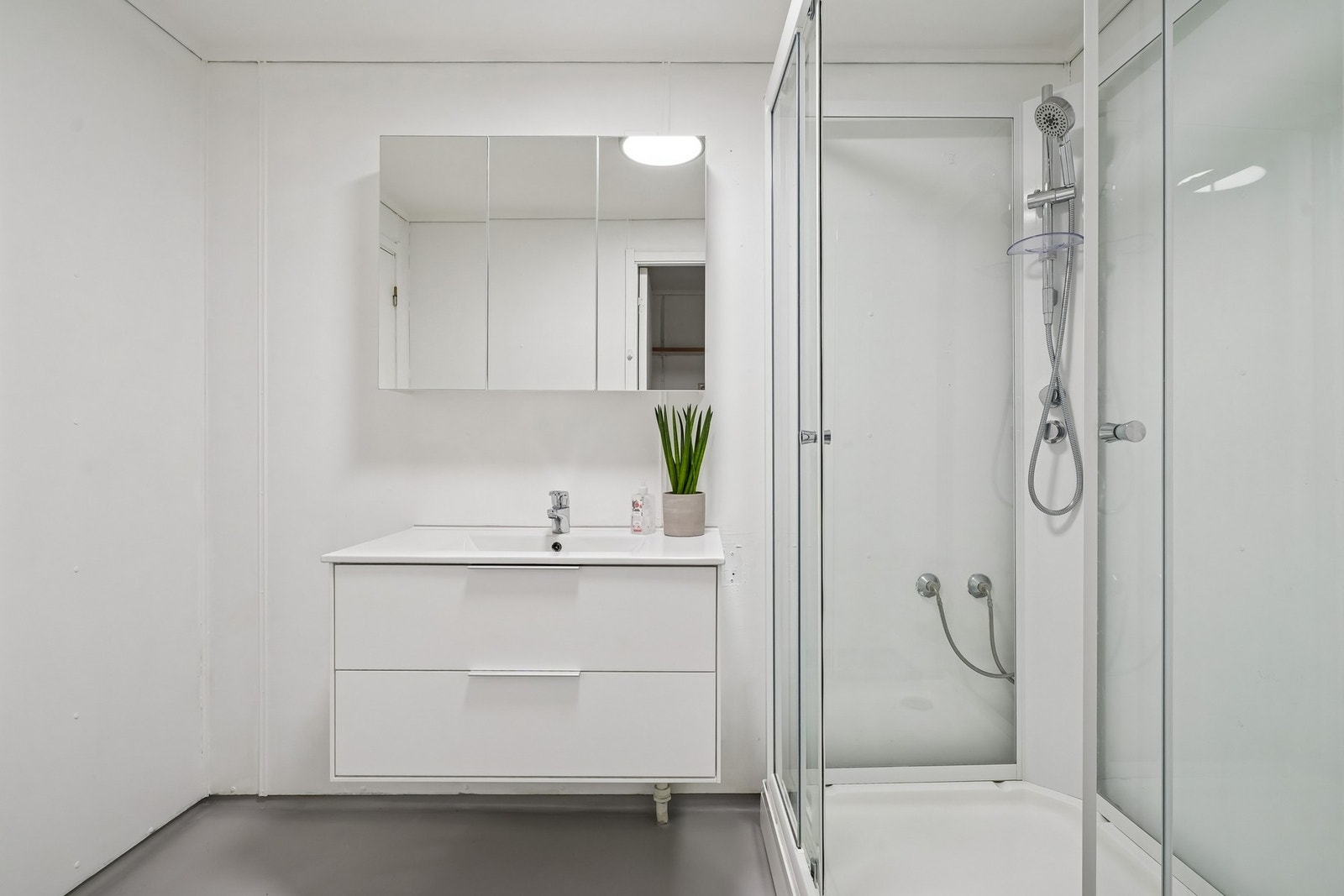 Innredet med servantinnredning med heldekkende servant, speilskap og dusjkabinett. Galleribilde