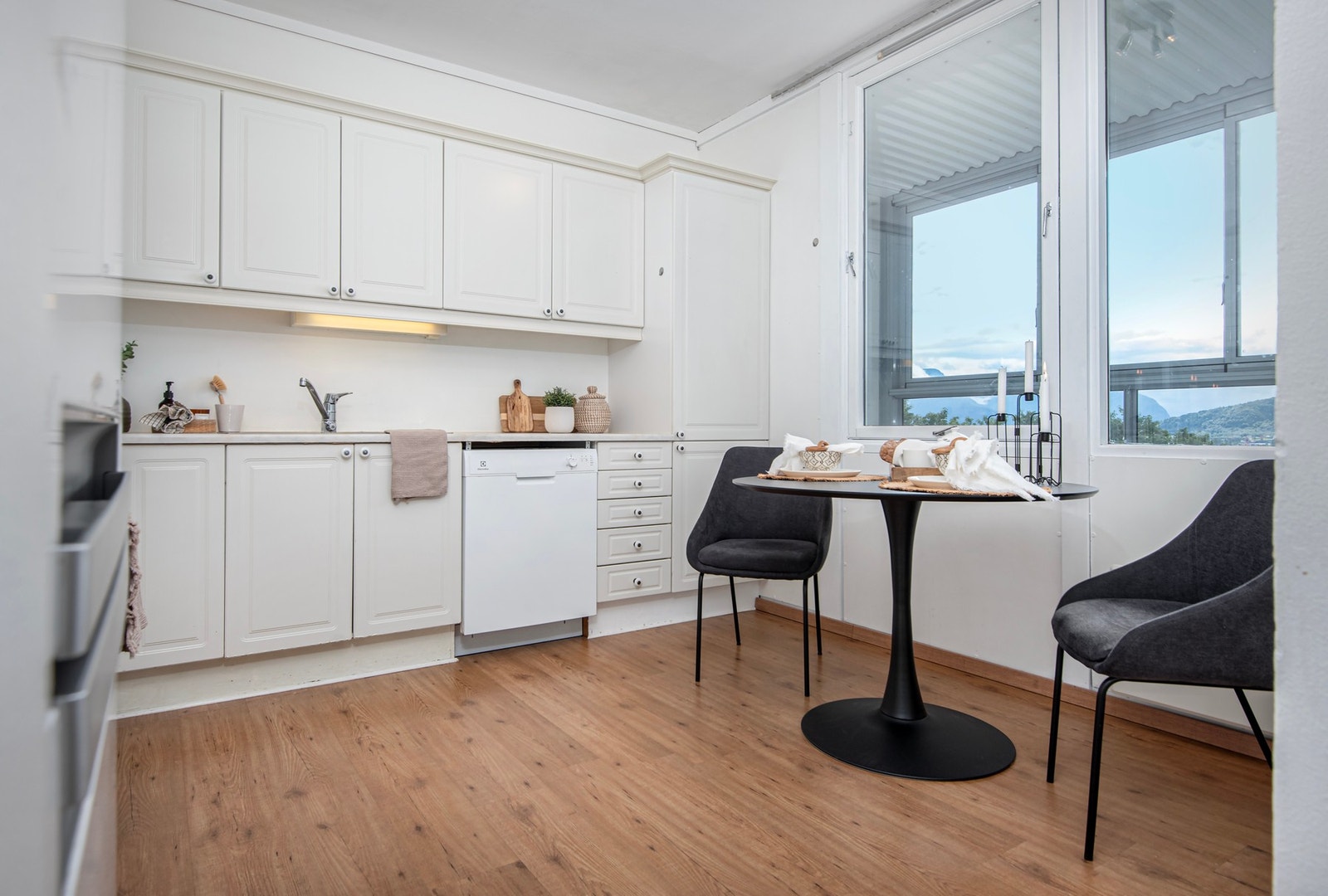 Kjøkkeninnredning med hvite profilerte fronter og laminat benkeplate. Galleribilde