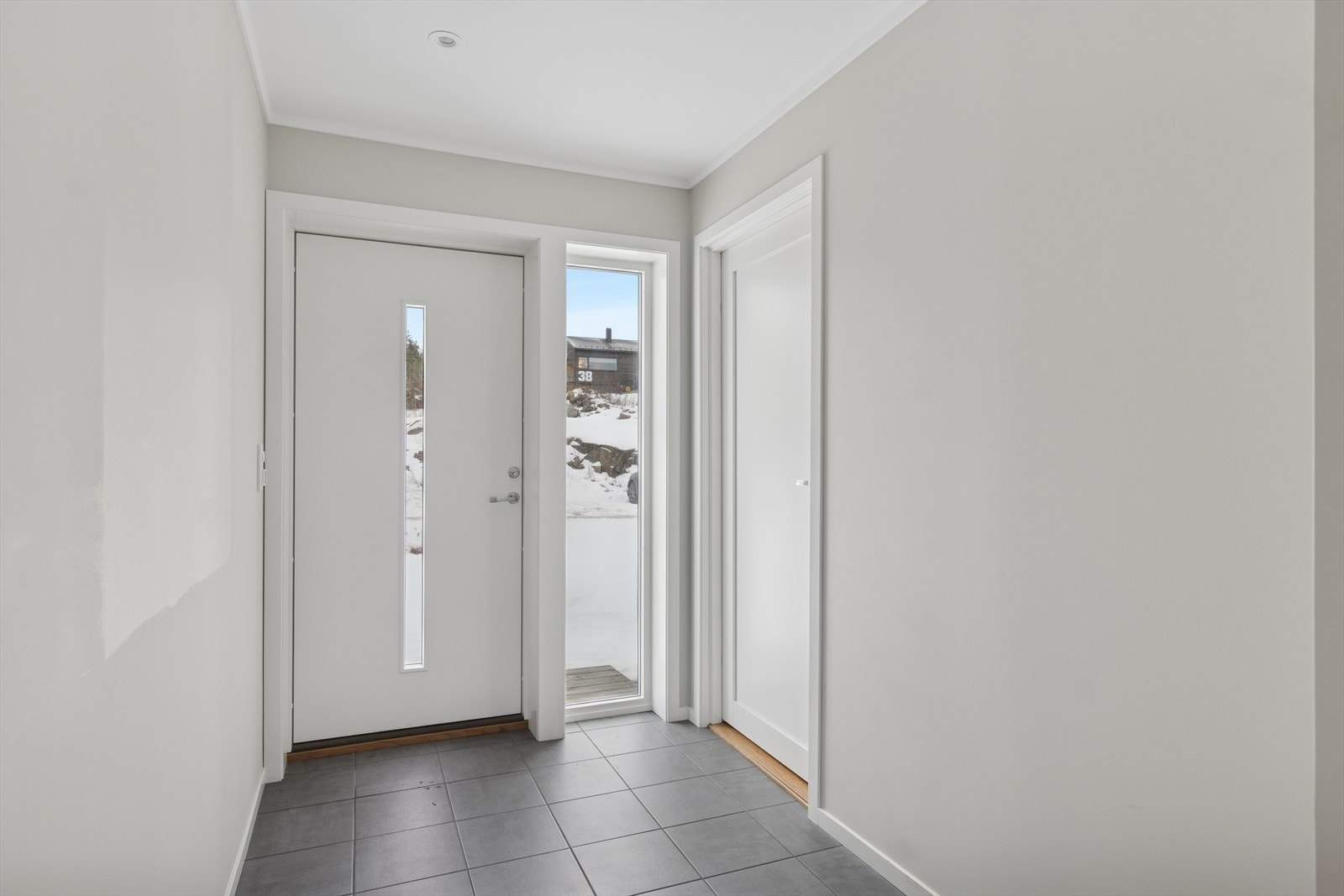 Det er adkomst til boligen fra bakkeplan, og inn i første etasje. Velkommen inn - her ønskes du velkommen inn i lys entrè med plass til å henge fra deg ytterklær. Galleribilde