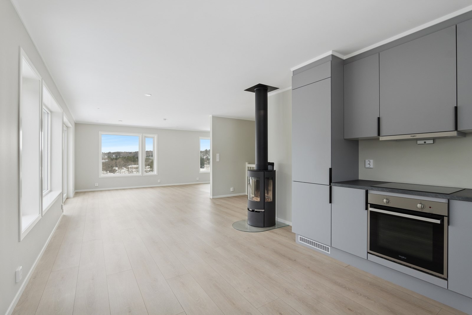 En pen ovn for vedfyring er fint plassert slik at den varmer godt inn på kjøkken og stue. Galleribilde