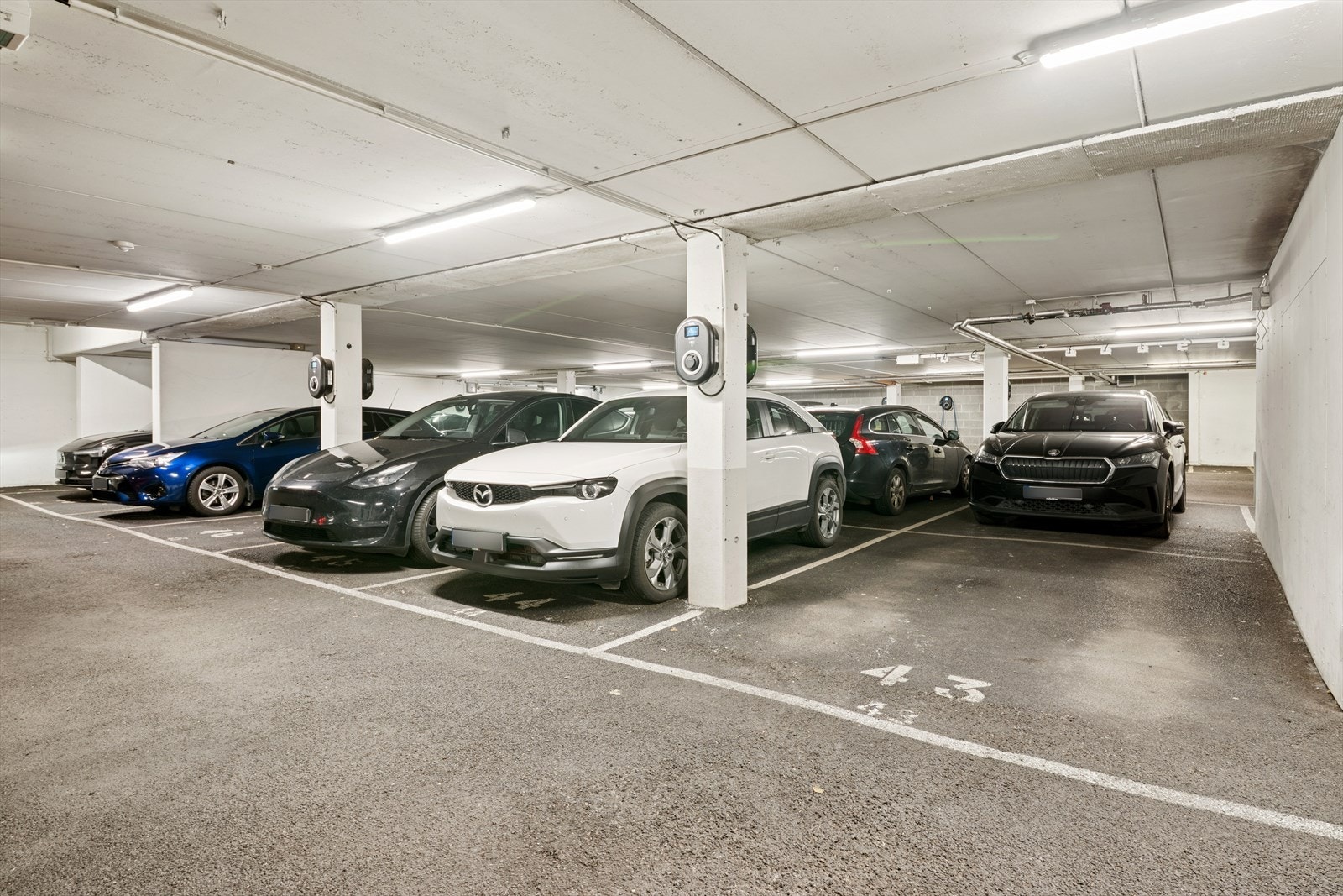 Parkeringsplass i felles garasjeanlegg med elbillader. Galleribilde