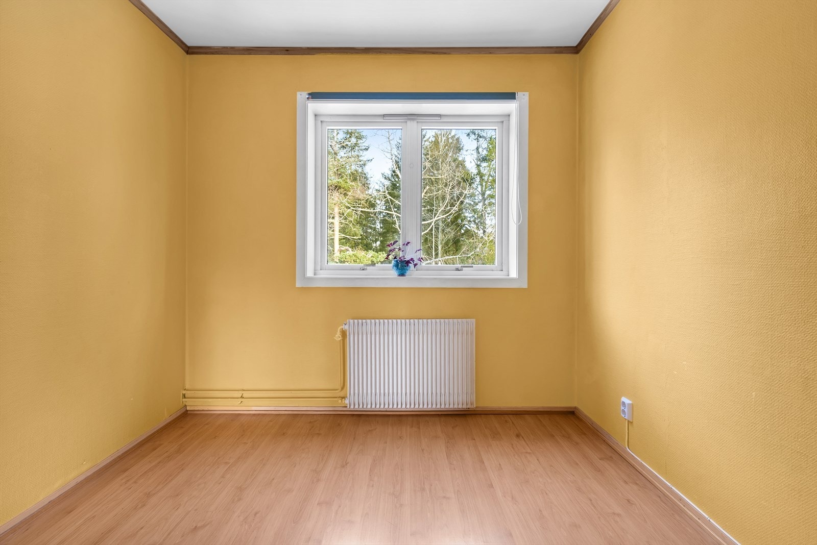 Det ene av leilighetens to soverom, med laminat på gulv og oppvarming via radiator. Galleribilde