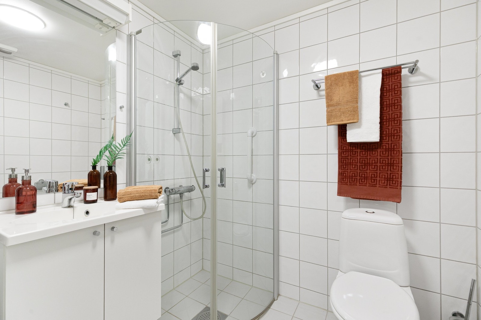 Bad nr. 2 er også flislagt. Her er det baderomsinnredning, gulvmontert toalett, dusjhjørne med glassvegger og opplegg til vaskemaskin. Galleribilde