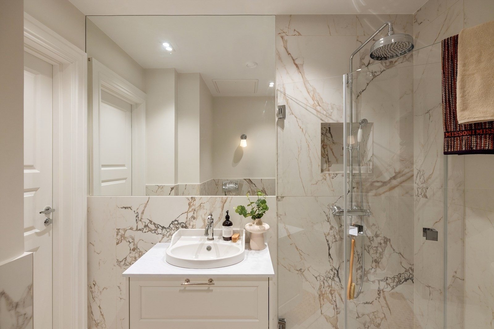 Baderommet har innredning med nedfelt servant, veggmontert toalett og dusjvegger/hjørneløsning. Galleribilde