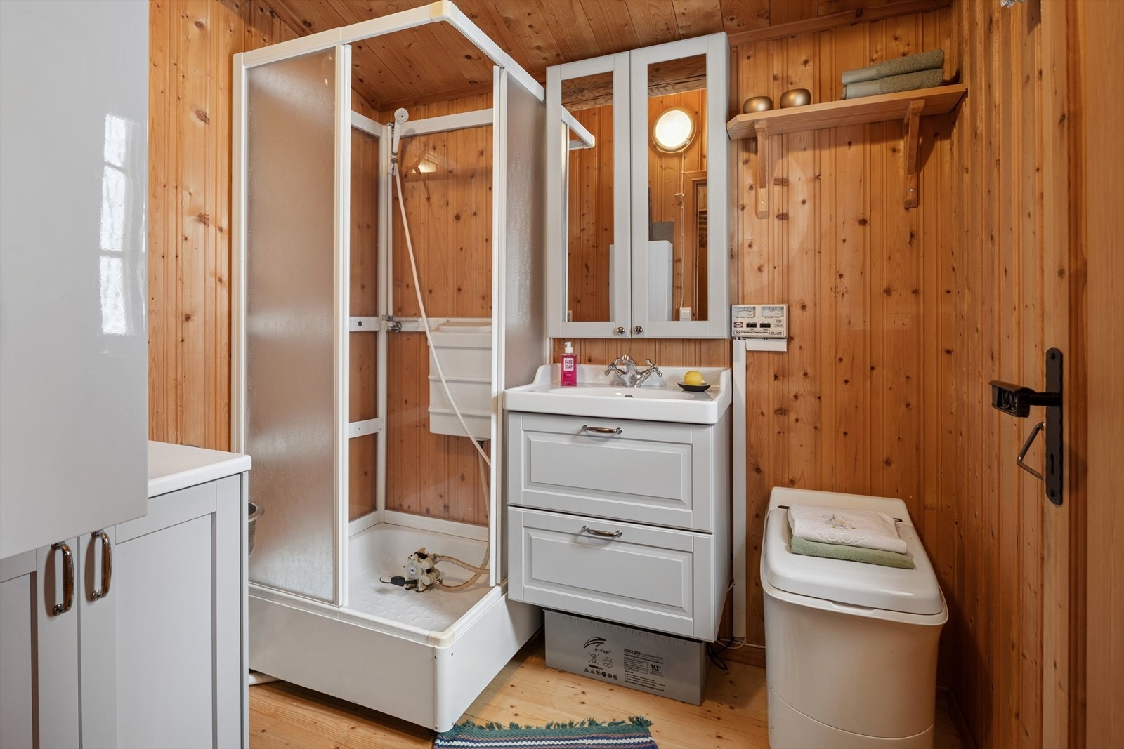 Sanitærrom med dusjkabinett med pumpesystem. Servant med tilhørende underskap og speilskap. Cinderella forbrenningstoalett. Ca. 14 liters varmtvannsbereder. Sanitærrommet er tilkoblet eget solcelleanlegg. Galleribilde