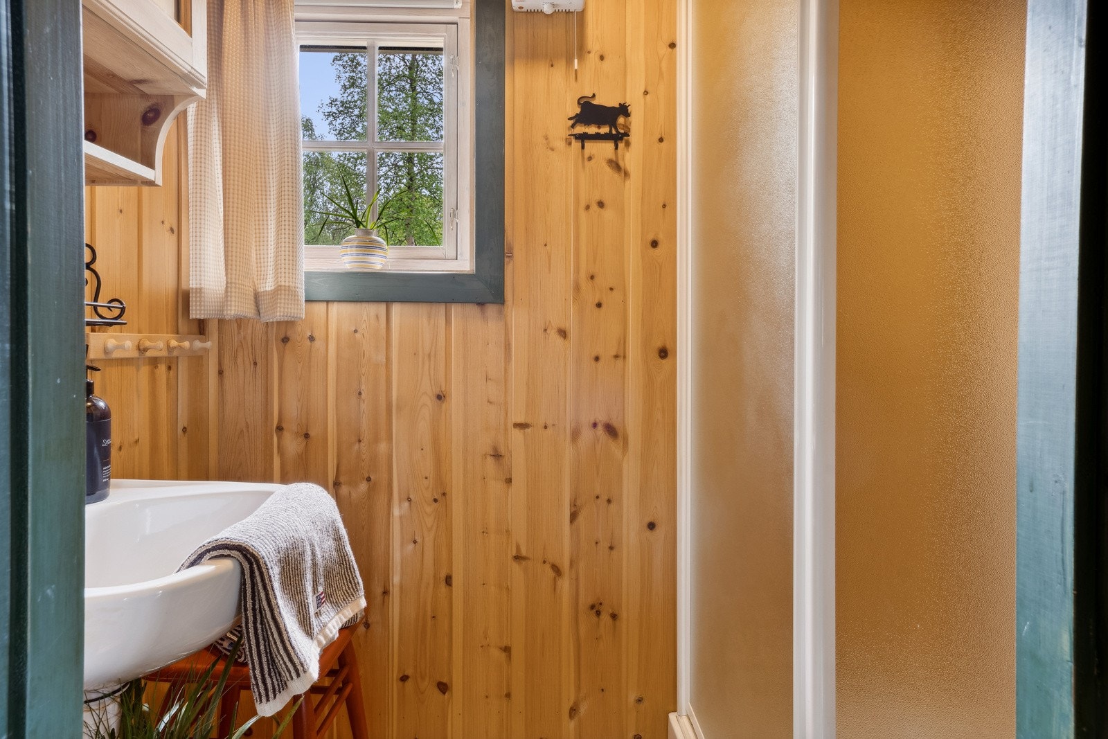 Badet i generasjonsdelen har paneloverflater, tregulv, dusjkabinett, servant og speilskap. Et vindu gir friskt dagslys. Galleribilde