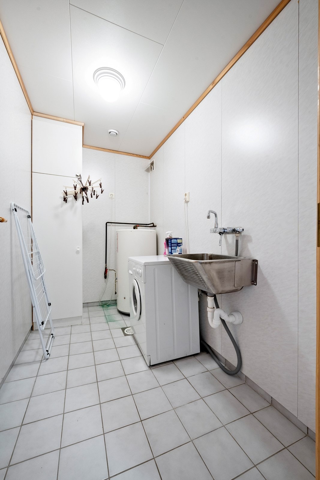 Vaskerom med fliser på golv og opplegg for vaskemaskin, utslagsvask og varmtvassberedar Galleribilde