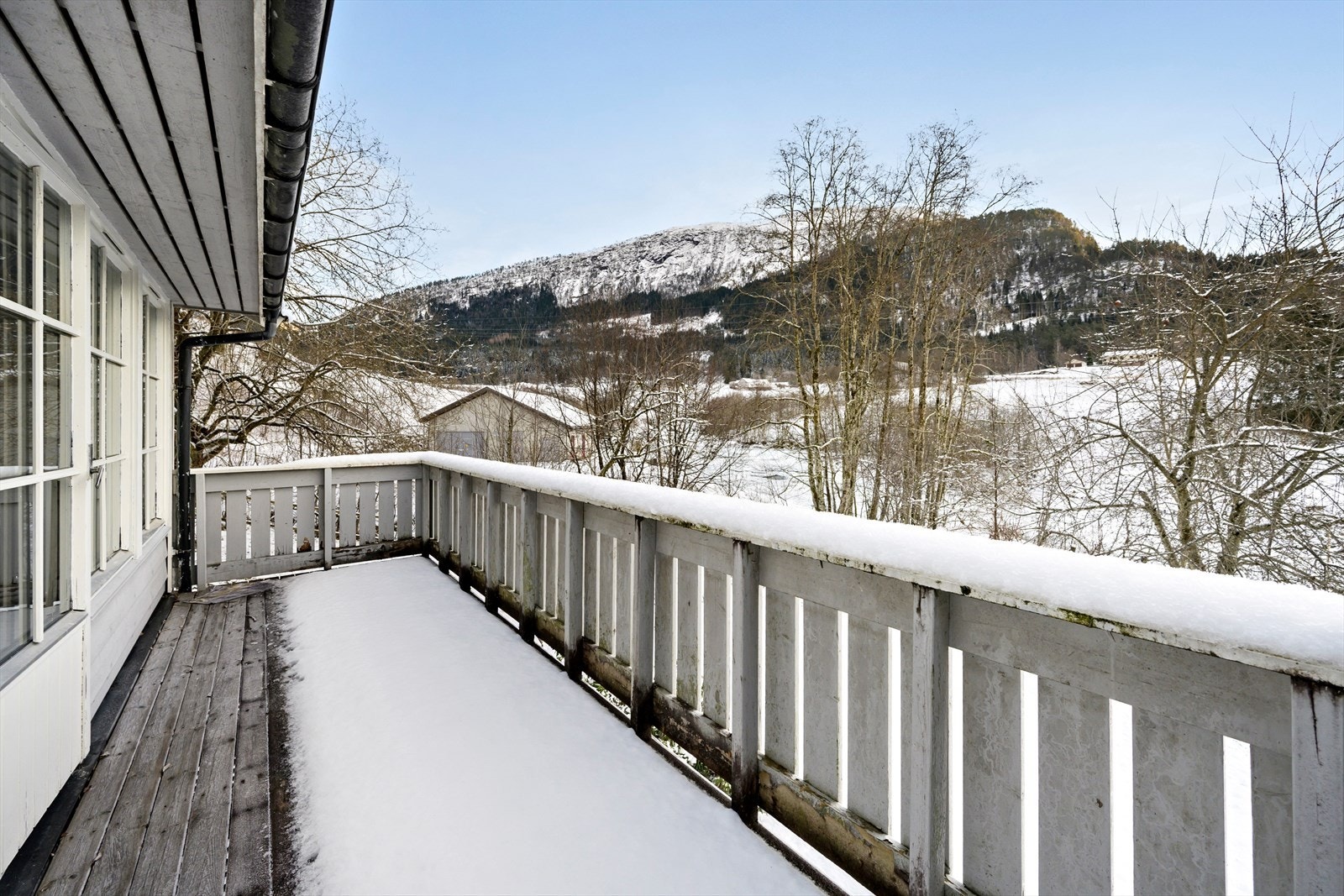 Usjenert og landleg utsikt mot slåttemark og elva Galleribilde