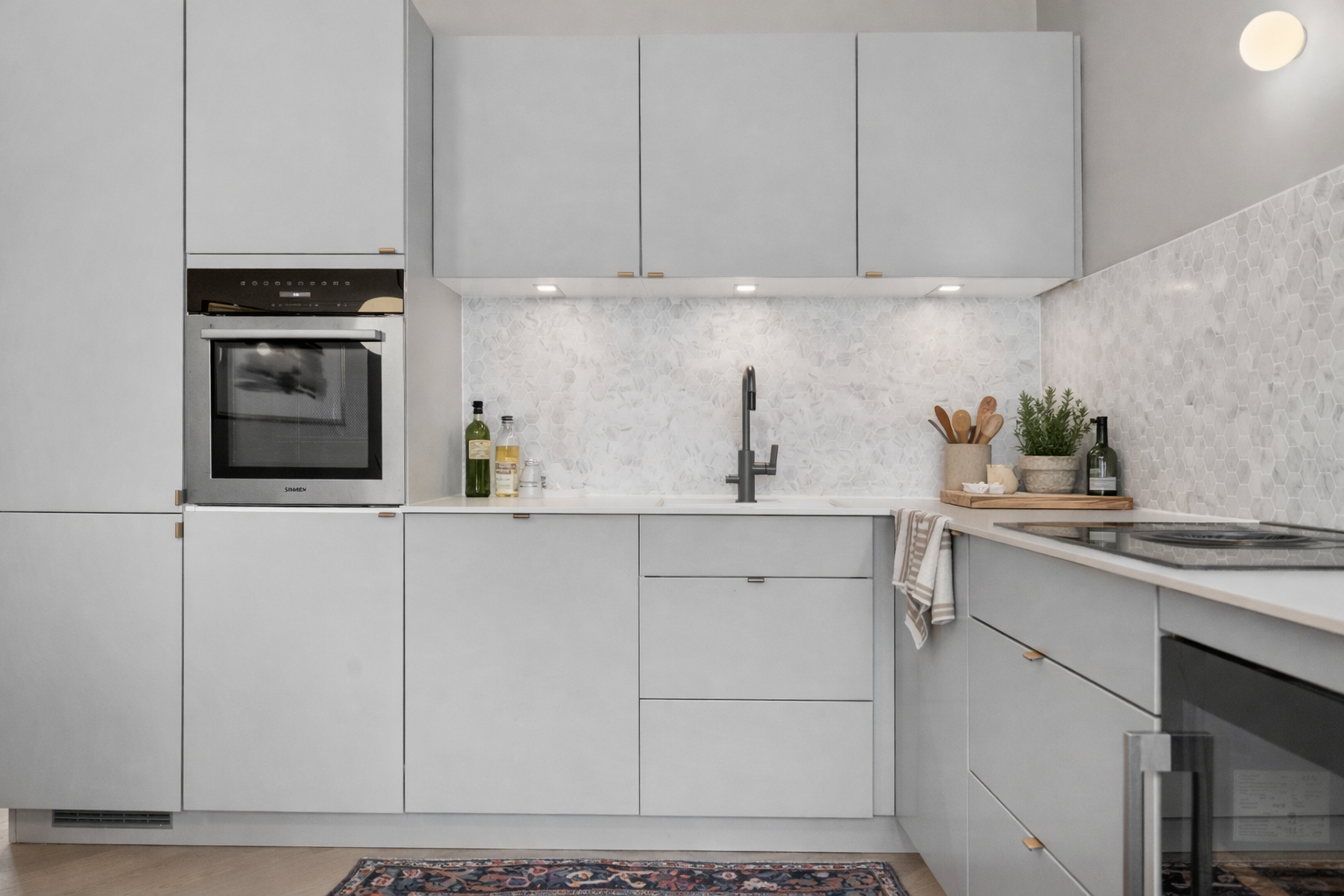 Det er hexagon marmor fliser over kjøkkenbenken. Integrerte hvitevarer. Galleribilde