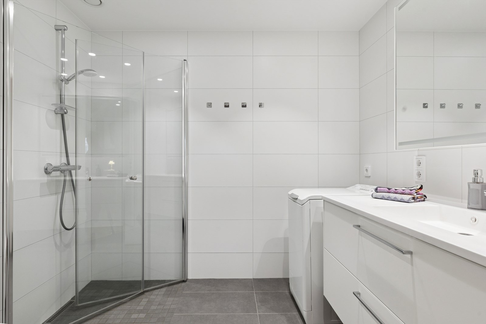 Lyst og tidløst baderom med flislagte overflater og gulvvarme. Galleribilde