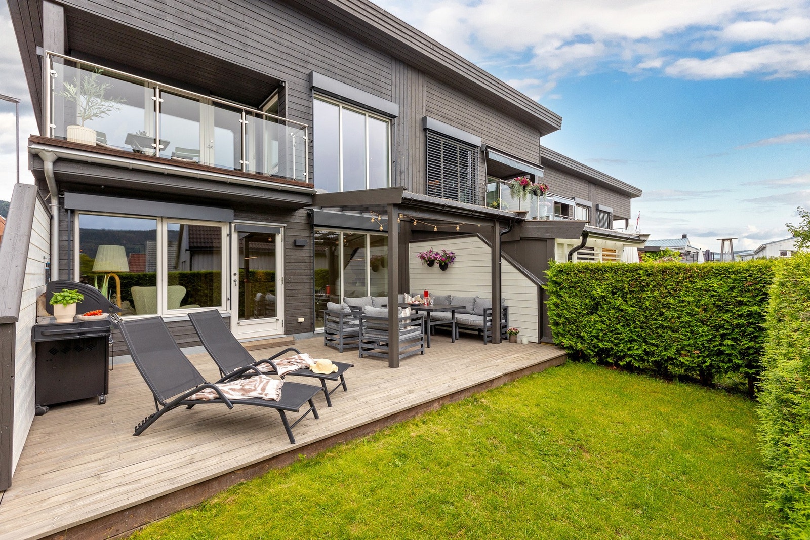 Grønn og velholdt hageflekk som skaper en koselig ramme rundt uteplassen. Galleribilde