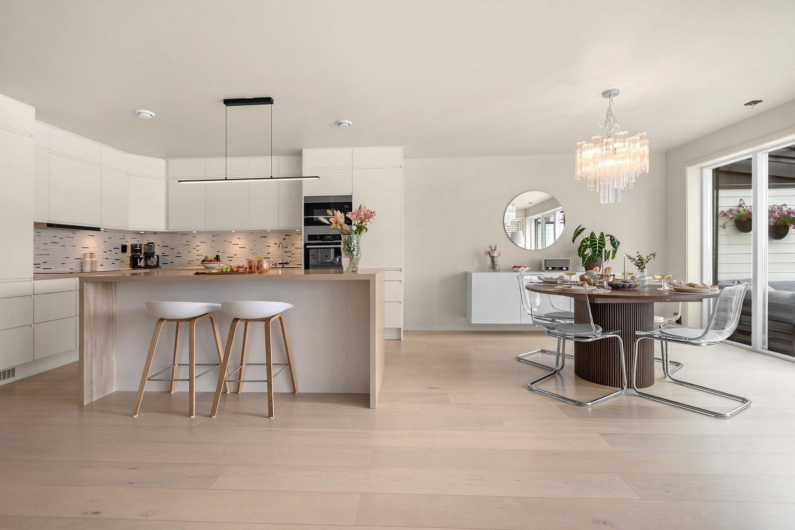 Lyst og moderne oppholdsrom med kjøkken, spiseplass og stue i åpen løsning - et sosialt midtpunkt i hjemmet. Galleribilde