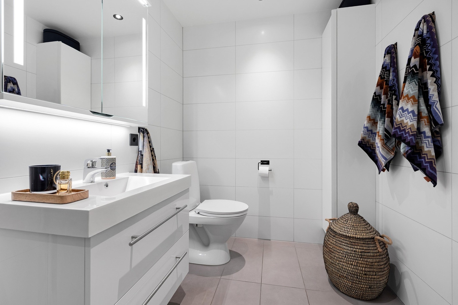 Lyst bad med god oppbevaringsplass, tidløse fliser og integrert belysning - en kombinasjon av funksjonalitet og komfort. Galleribilde