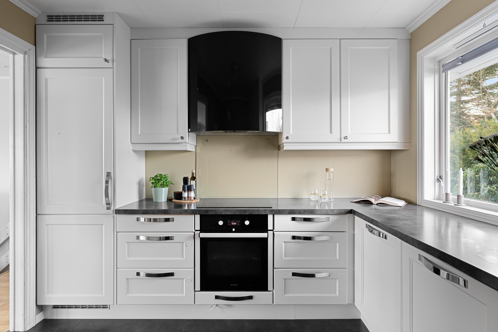 Innredningen har hvite, profilerte fronter og mørk benkeplate i laminat. Galleribilde