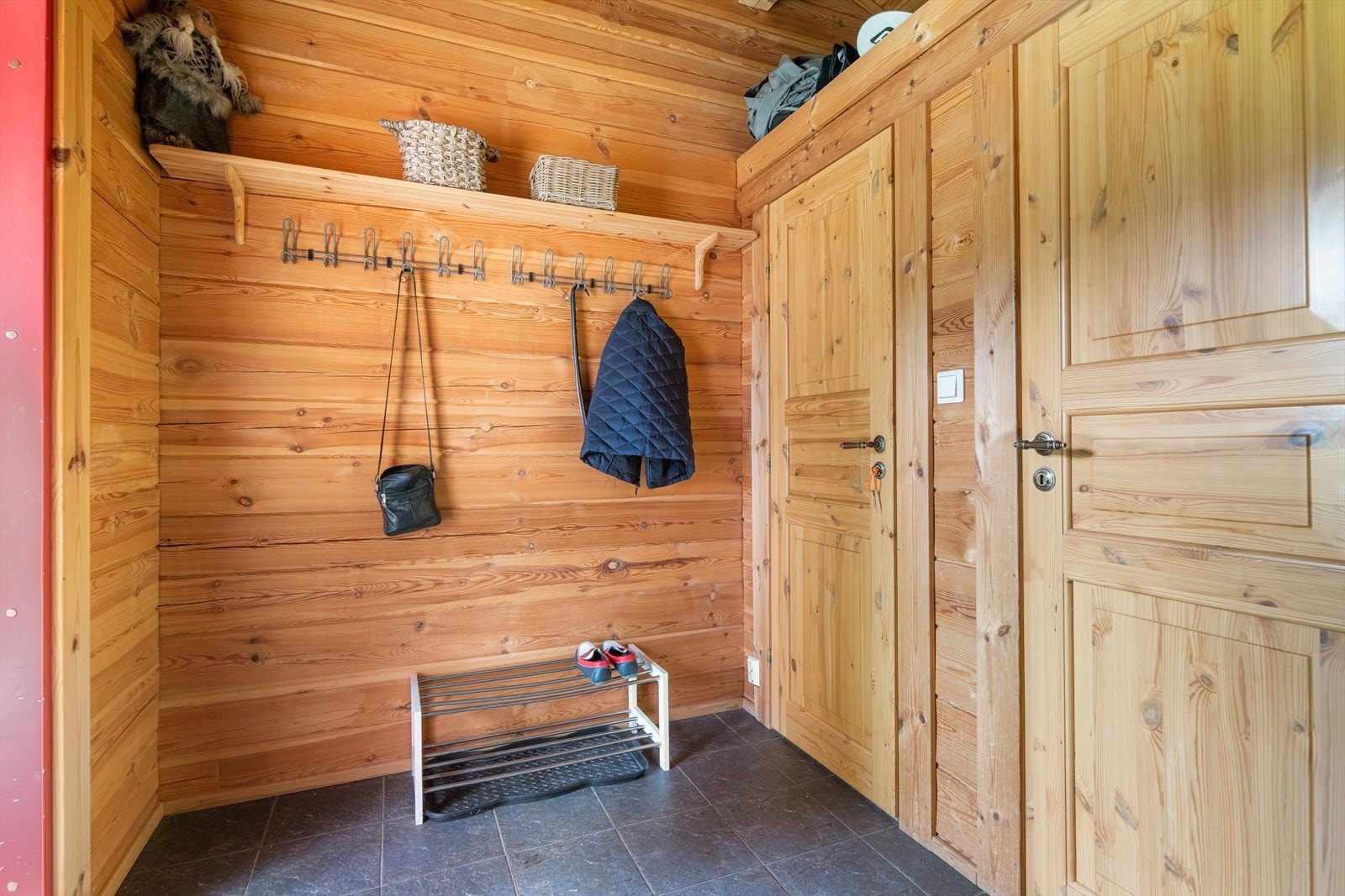 Hytta har et romslig gangareal med god plass til sko- og ytterklær. Inntil gangen er det to boder for oppbevaring. Sikringsskapet er plassert i en av bodene. Galleribilde