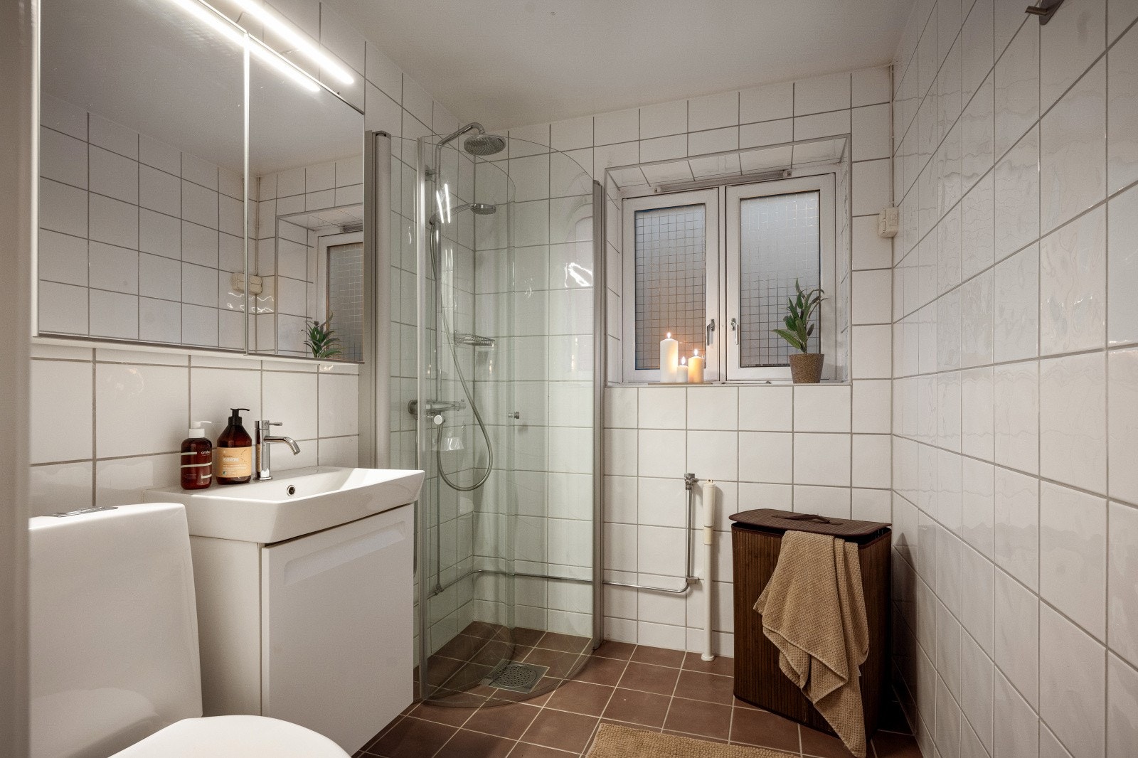 Baderommet er flislagt med varmekabler i gulv. Her er det nedfelt servant, gulvstående klosett, dusj på gulv med innfellbare dører i herdet glass, samt opplegg for vaskemaskin. Galleribilde