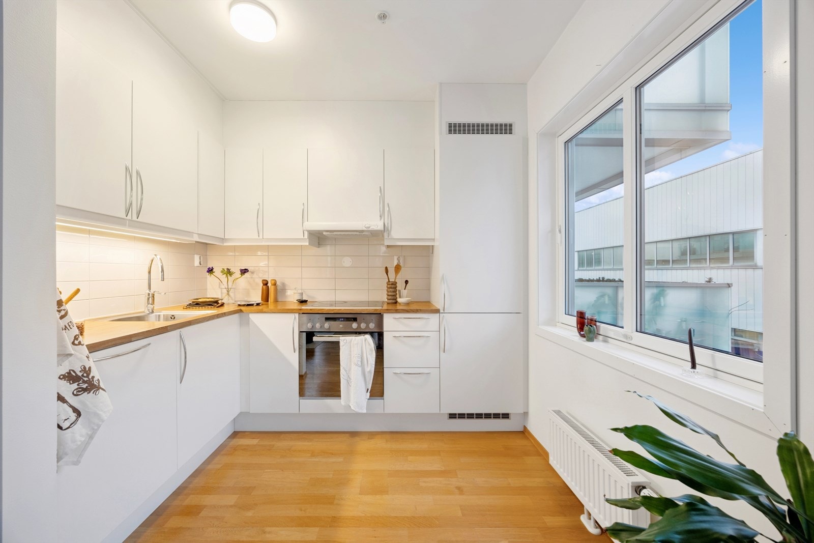 Kjøkkenet fremstår som både stilrent og funksjonelt, med hvite fronter og fliser over benkeplate i tre, som gir et moderne uttrykk. Galleribilde