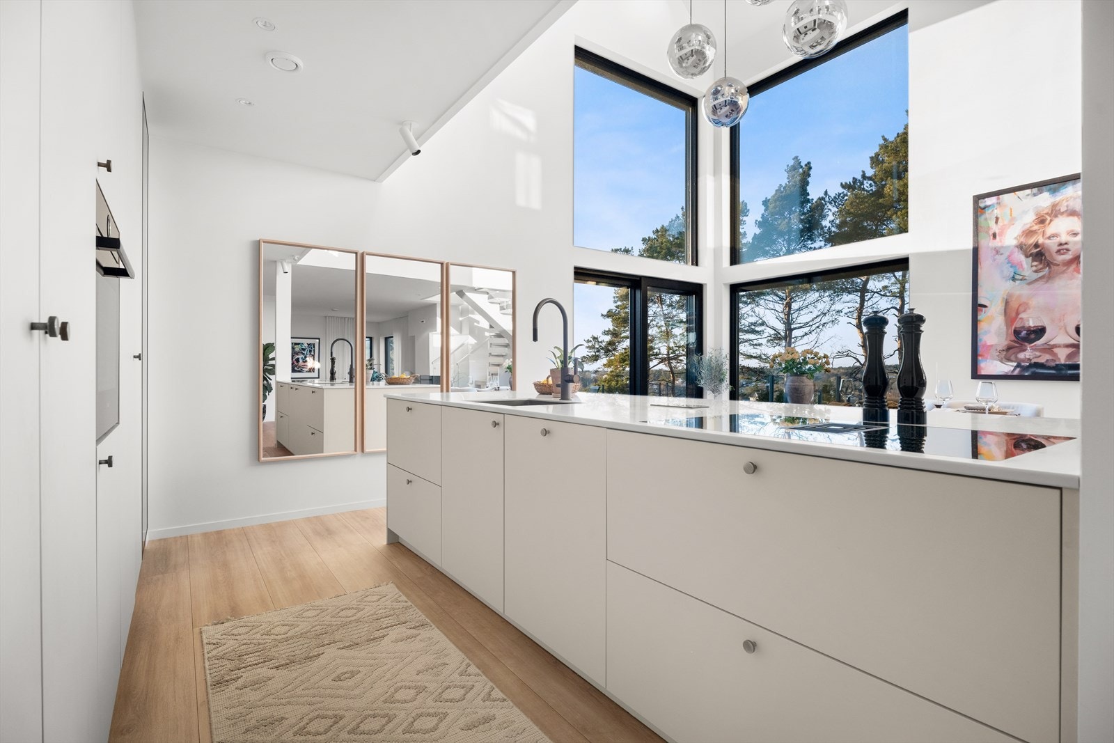 Kjøkkenet har en stilren innredning med glatte fronter, benkeplate av stein eller lignende materiale, og en praktisk kjøkkenøy. Galleribilde