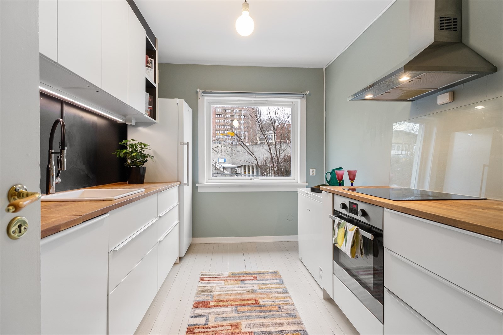 Lekkert IKEA kjøkken i separat rom fra stuen. Innredning bestående av glatte fronter, benkeplate i heltre, toppmontert vask og ettgreps kjøkkenarmatur med spylefunksjon. Galleribilde