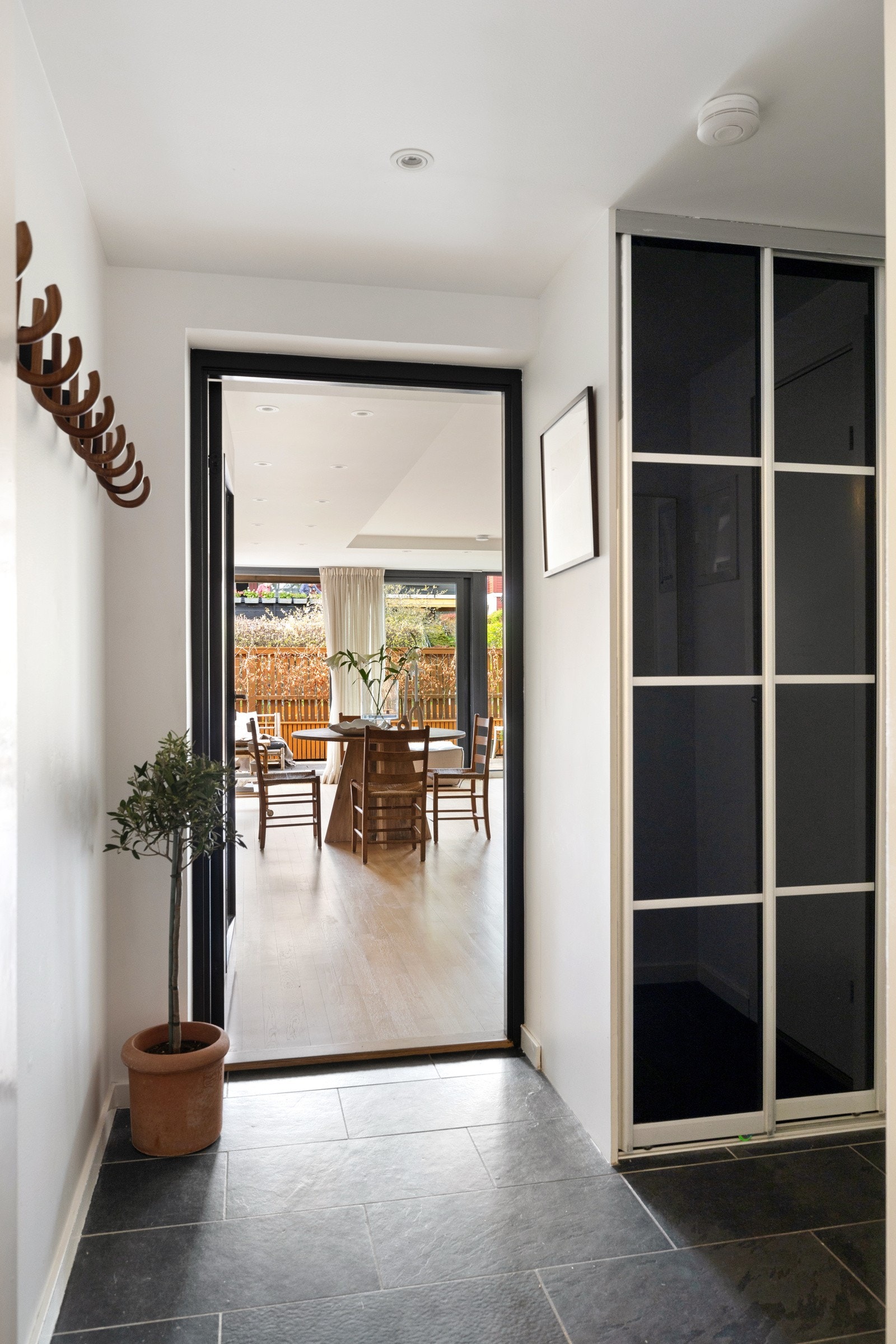 Entréen har lysmalte veggflater, fliser på gulv, downlights i himling og skyvedørsgarderobe Galleribilde