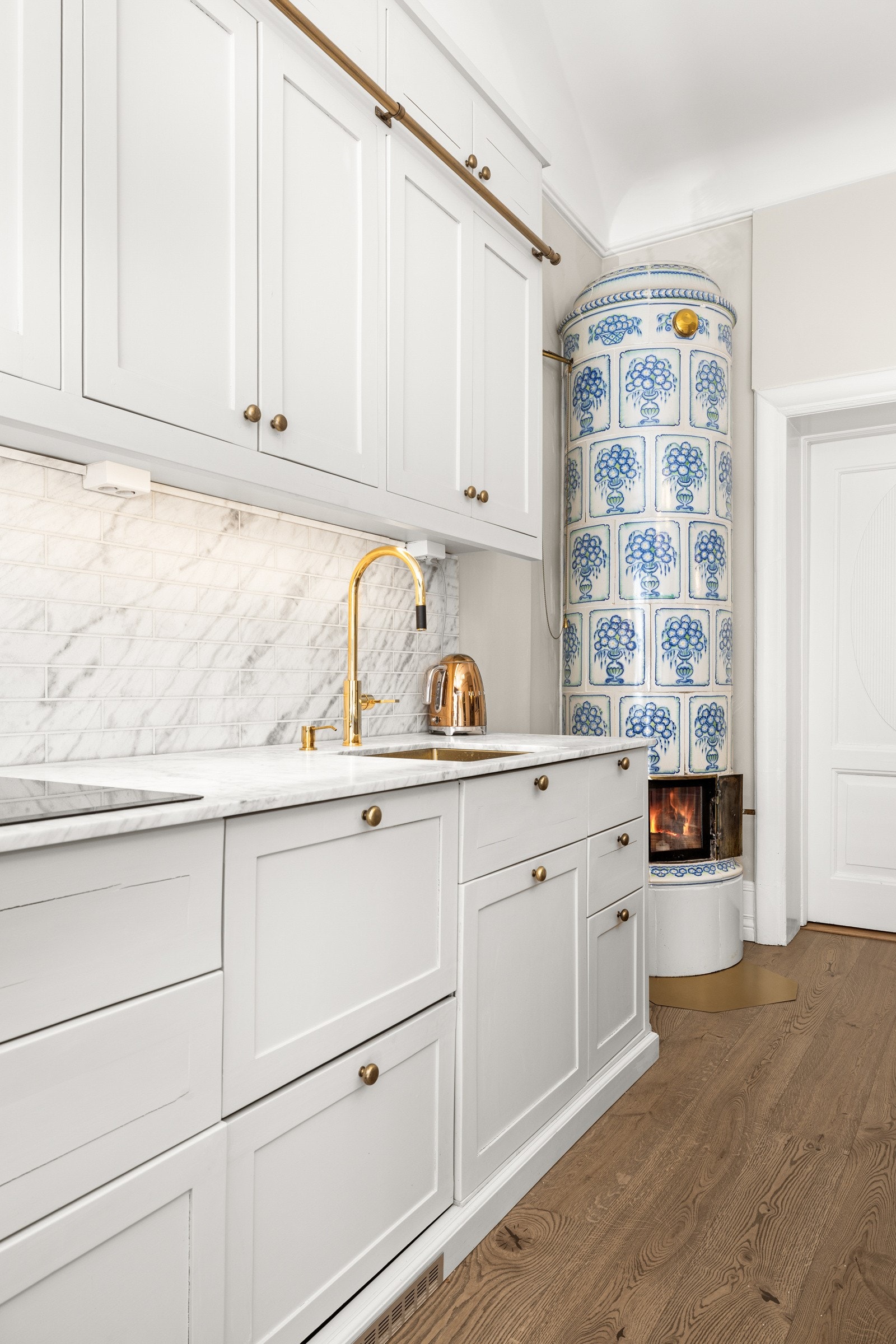 Kakkelovnen i hjørnet tilfører kjøkkenet en sjelden dybde og karakter - et varig symbol på både tradisjon og varme. Galleribilde