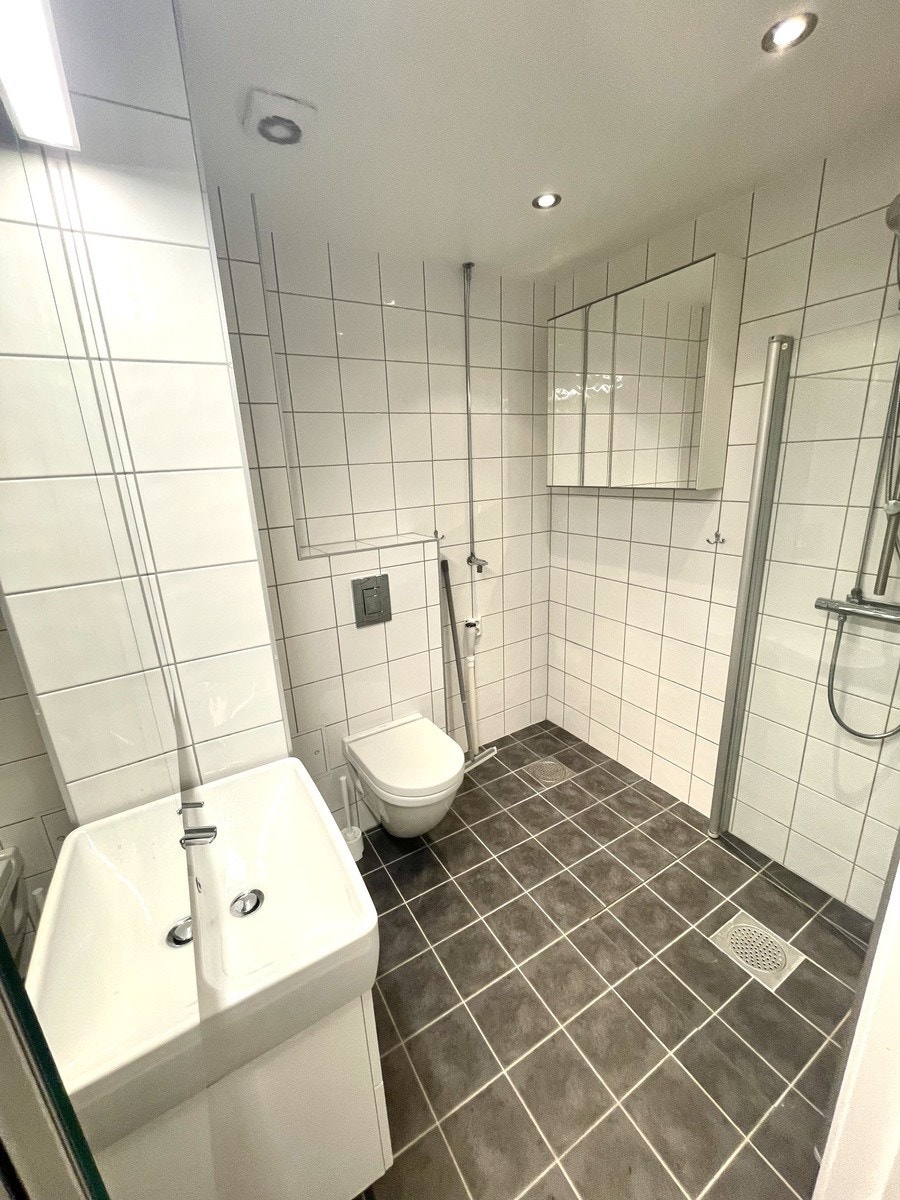 Bad sett fra gang. Vakskemaskin er ikke nødvendig da det er vaskeri i etg. under leiligheten. Tar noen sekunder å gå dit. Alternativt er det bare for leietaker å sette inn vaskemaskin om det er ønsket. Galleribilde