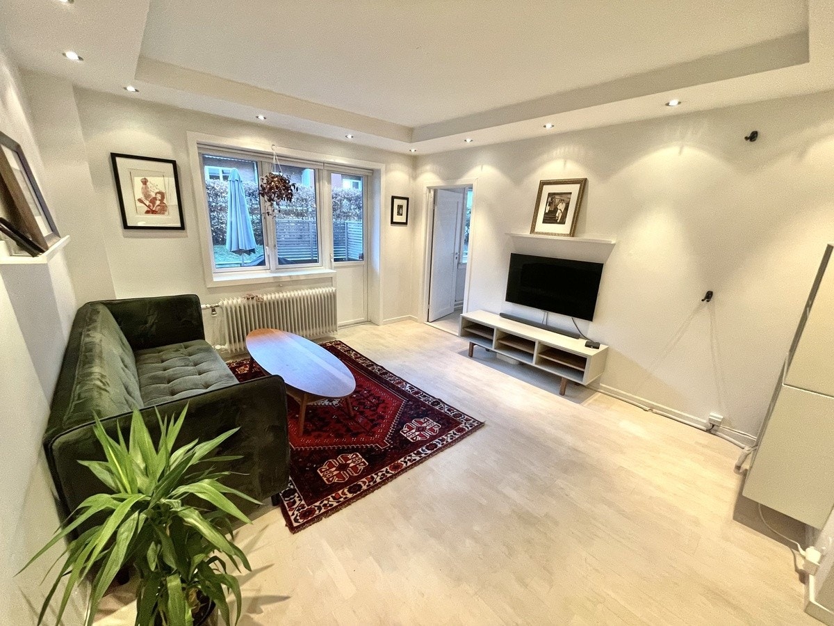 Stue med Samsung tv, bord, sofa og hyller. Galleribilde