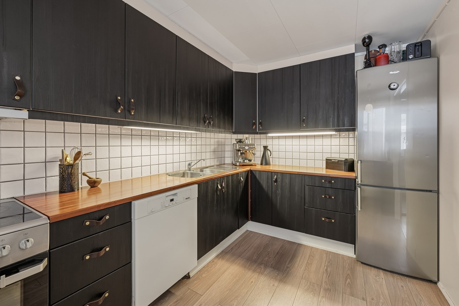 Kjøkkenet har en mørk innredning med laminerte skrog og glatte folierte fronter. Galleribilde