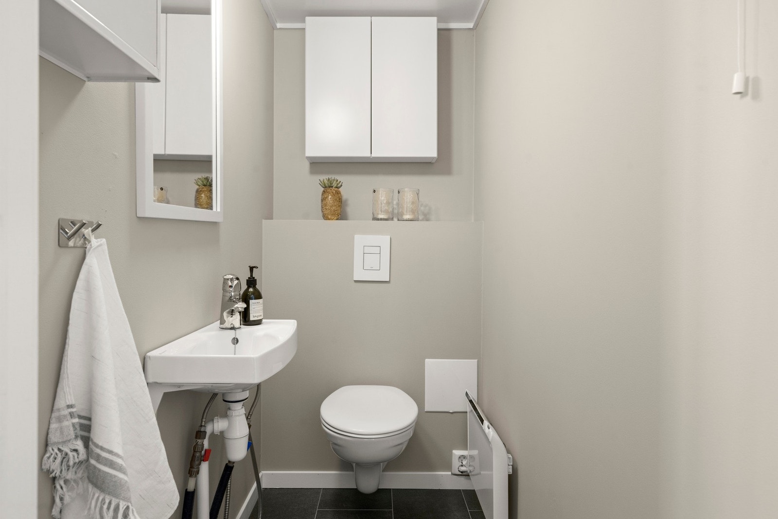 Toalettrom har malte slette flater på vegger, å fliser på gulv. Innredet med håndvask, skap, panelovn og vegghengt vannklosett. Naturlig ventilasjon. Galleribilde