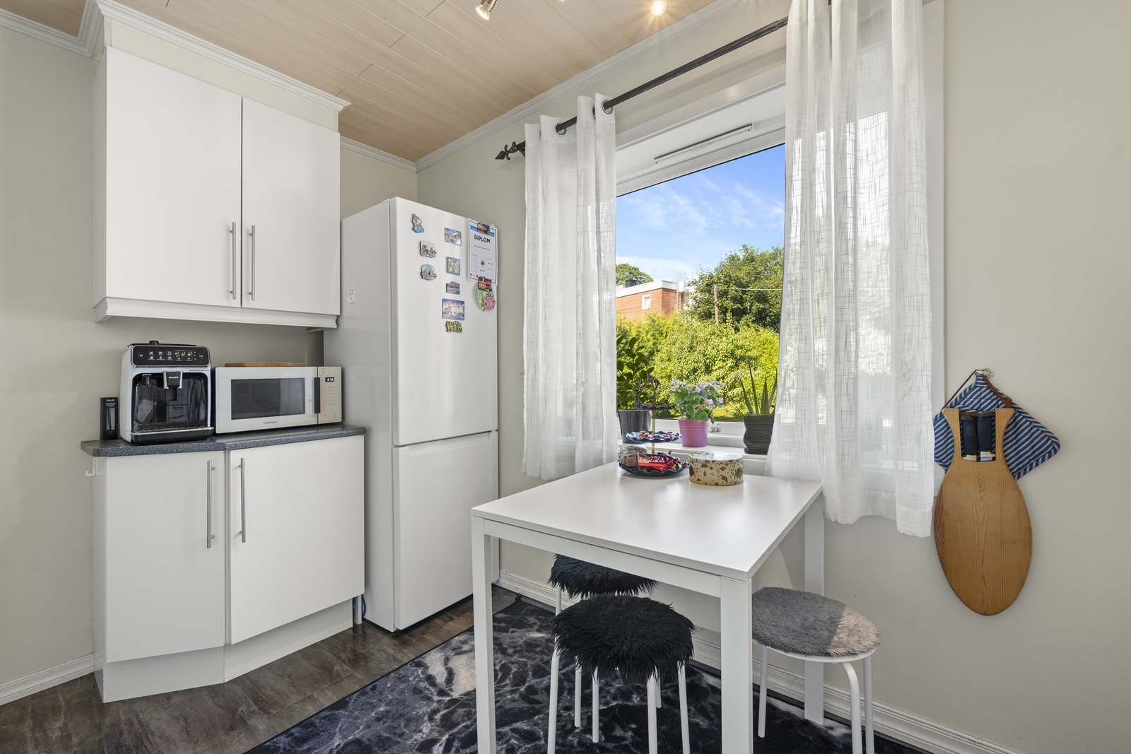 Praktisk løsning med nisje for både oppvaskmaskin, kjøleskap og komfyr, samt integrert avtrekksvifte plassert i overskap Galleribilde