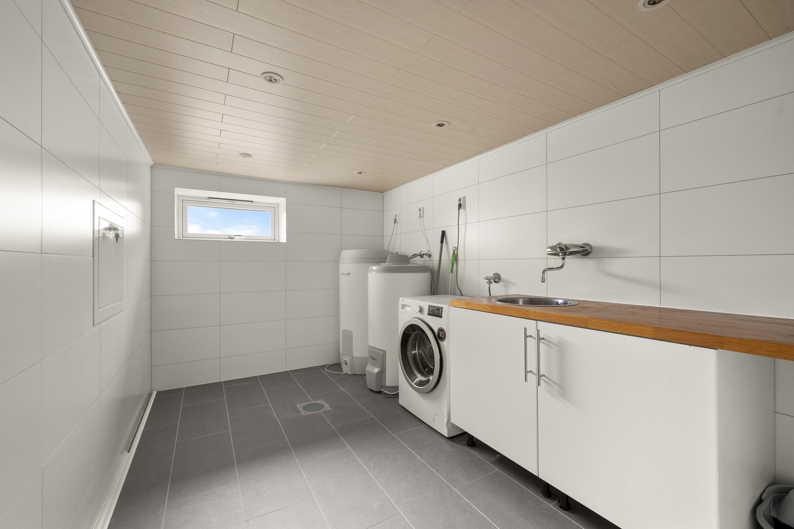 Flislagt vaskerom med utslagsvask og opplegg for vaskemaskin. Greit med arbeidsplass og naturlig ventilasjon Galleribilde