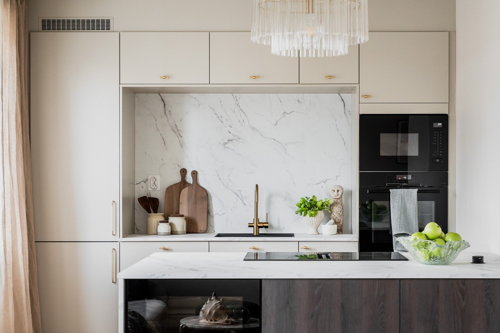 Stilrent kjøkken med marmorert bakplate, pop-up stikkontakt og lekkert armatur i børstet messing. Galleribilde