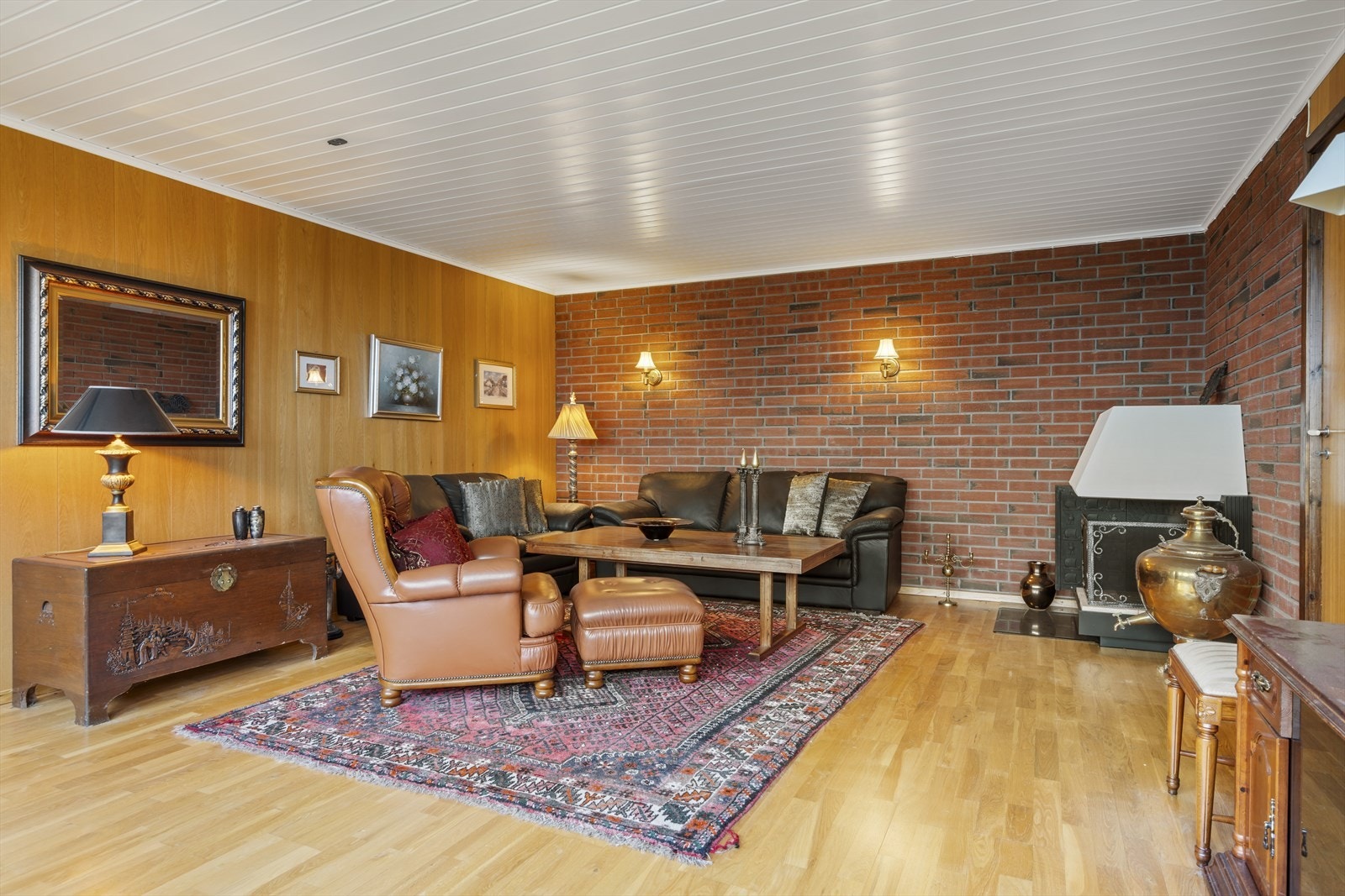 Kjekk kjellerstue med parkett på gulv, mur/panel på vegger. Varmepumpe, peis. Galleribilde