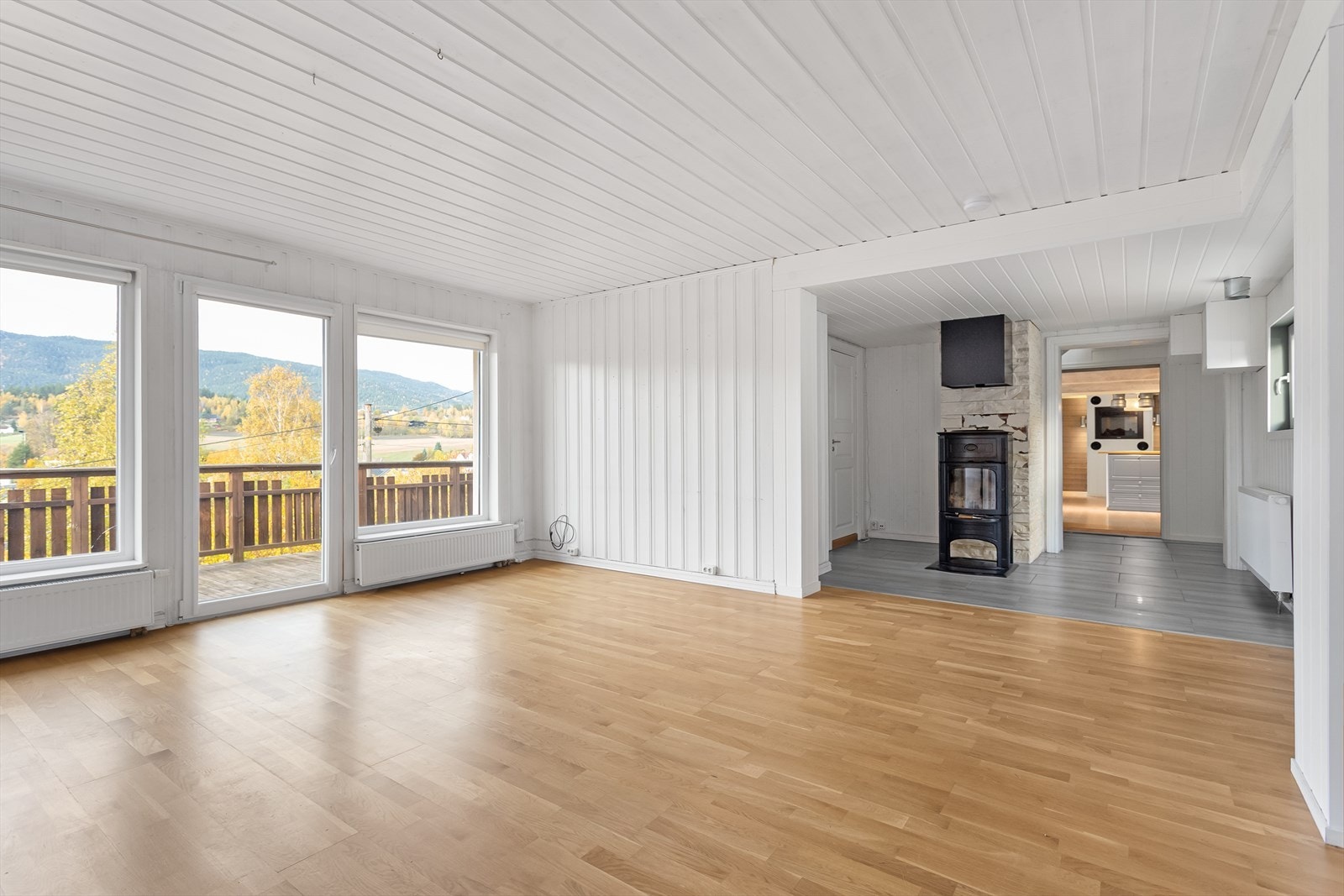 Pen stue med parkett på gulv og hvitmalt panel på vegg. Galleribilde