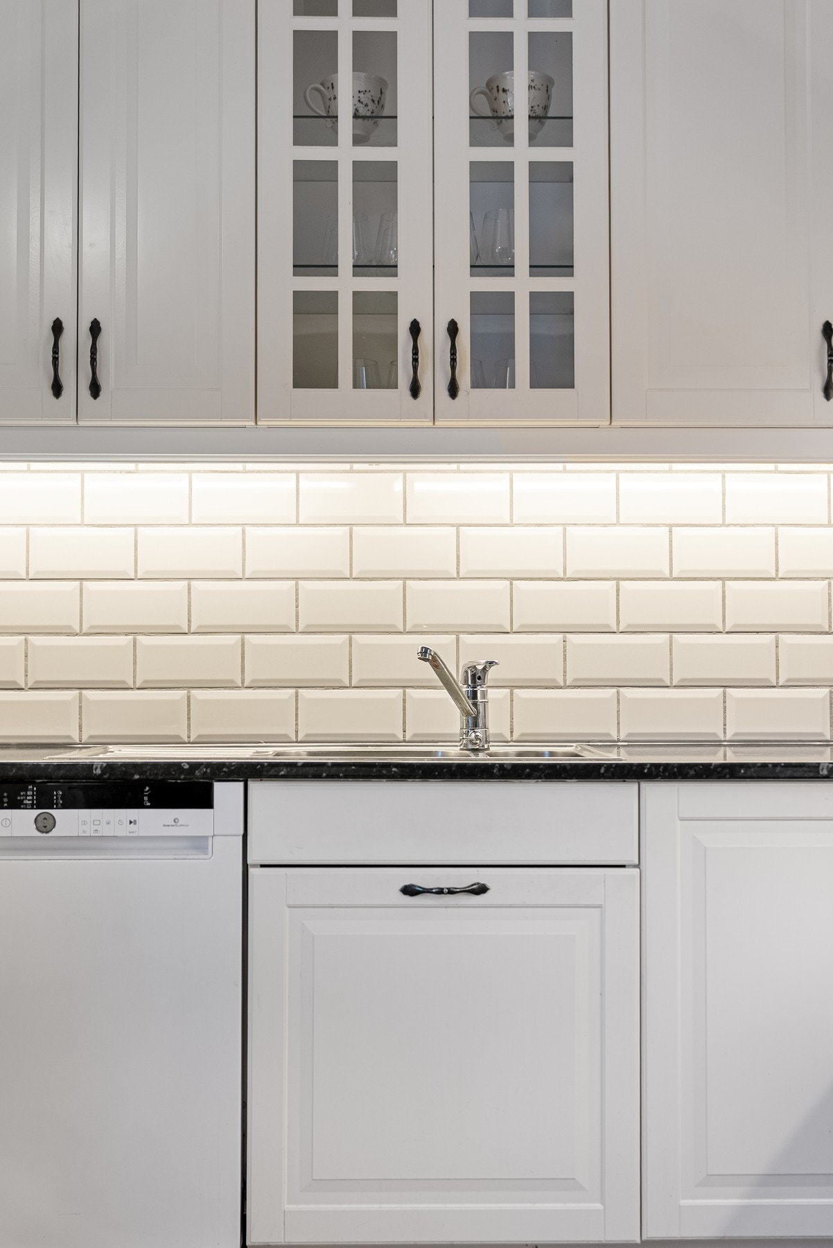 Mellom overskap og kjøkkenbenk har du godt arbeidslys i tillegg til fliser som gir et rent uttrykk og enkelt renhold Galleribilde