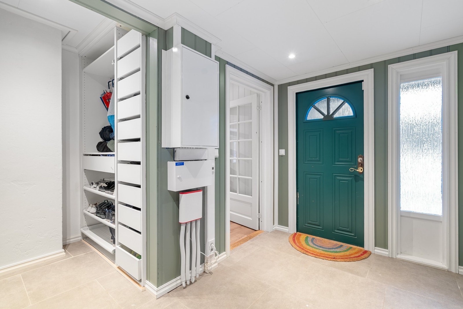 Innenfor døren blir du møtt av en lys entré med fliser og varmekabler på gulvet og eget område for ryddig klesoppbevaring Galleribilde