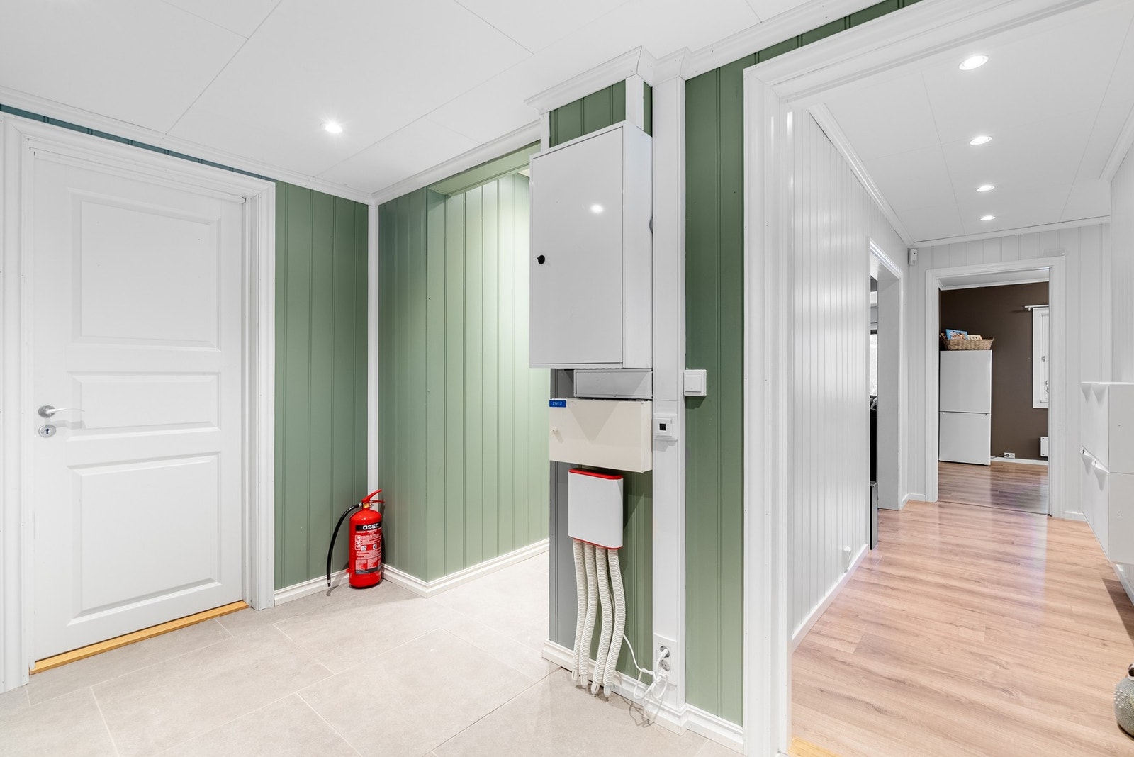 En åpen og luftig entré med lun og varm farge og godt lys fra downlights i taket Galleribilde