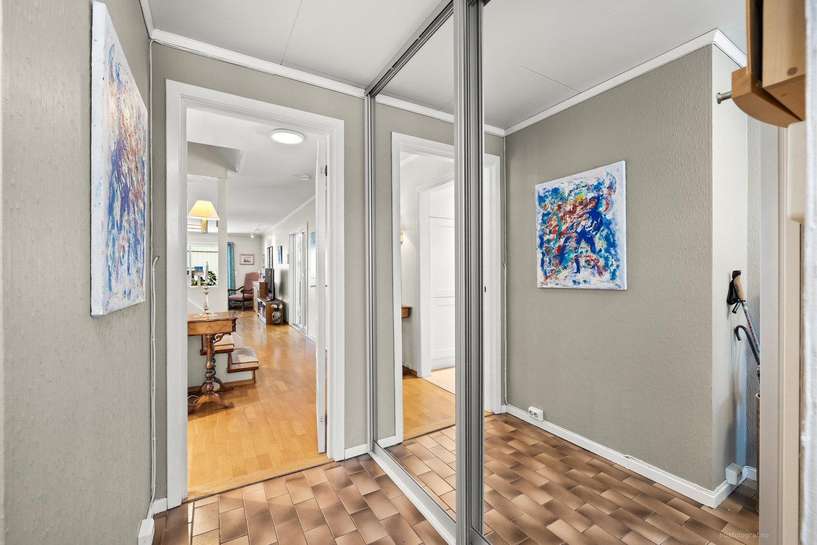 Entréen har flislagt gulv og et romslig garderobeskap med speilfronter for oppbevaring. Galleribilde