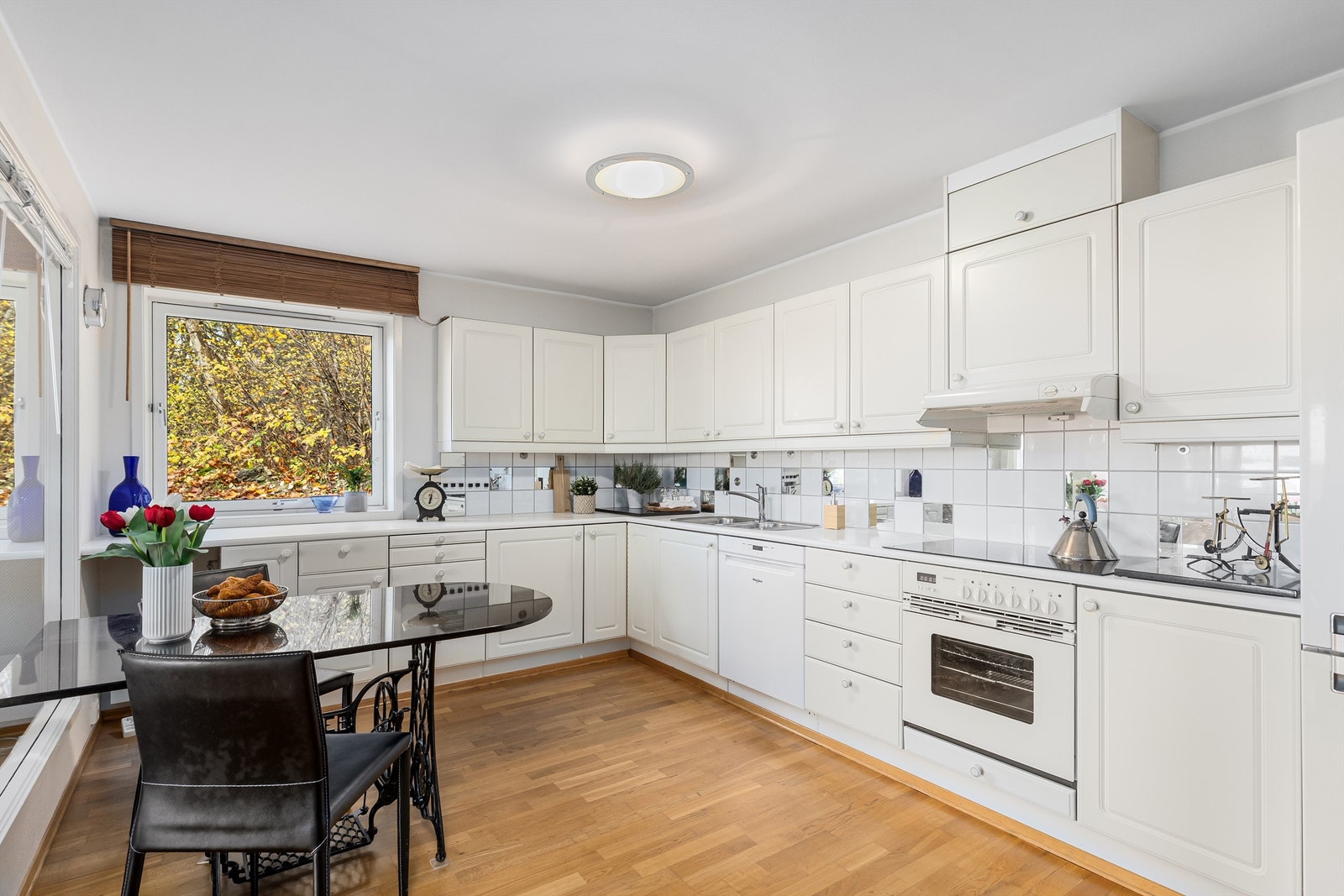 L-formet hvit kjøkkeninnredning med mye skap- og benkeplass Galleribilde