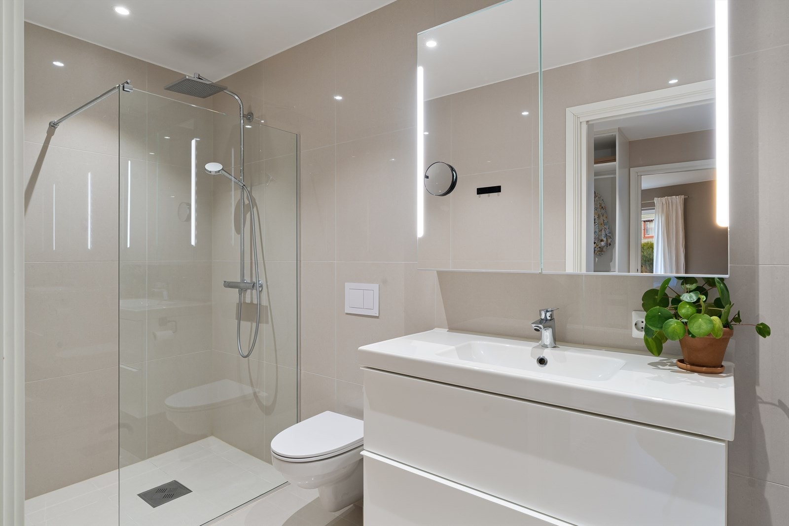 dusjhjørne m/fossefall dusjhode, vegghengt wc og pen seksjon med vask. Downlights i tak. Galleribilde