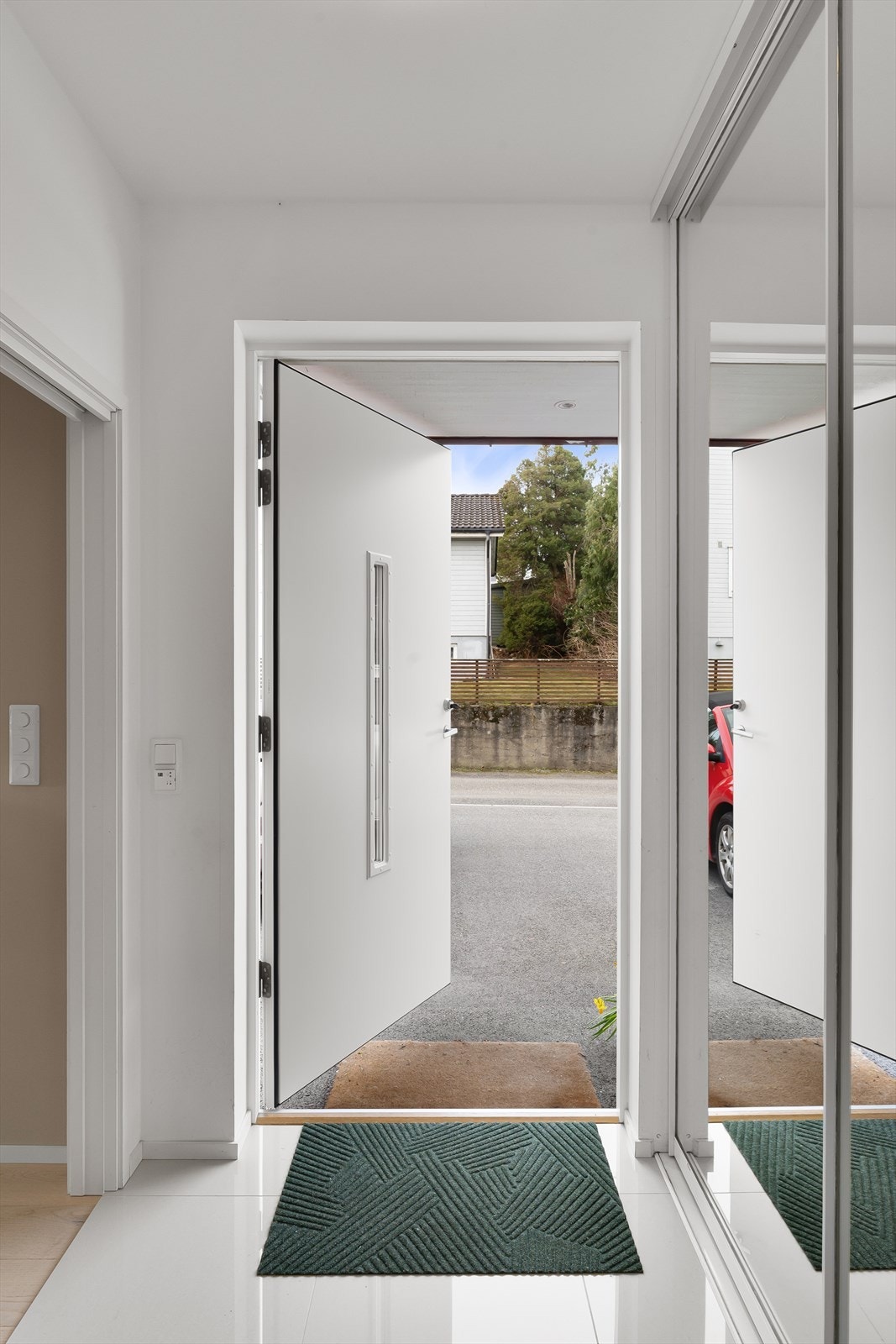 Innbydende entré med store fliser, gulvvarme og stor skyvedørsgarderobe med speilfronter Galleribilde