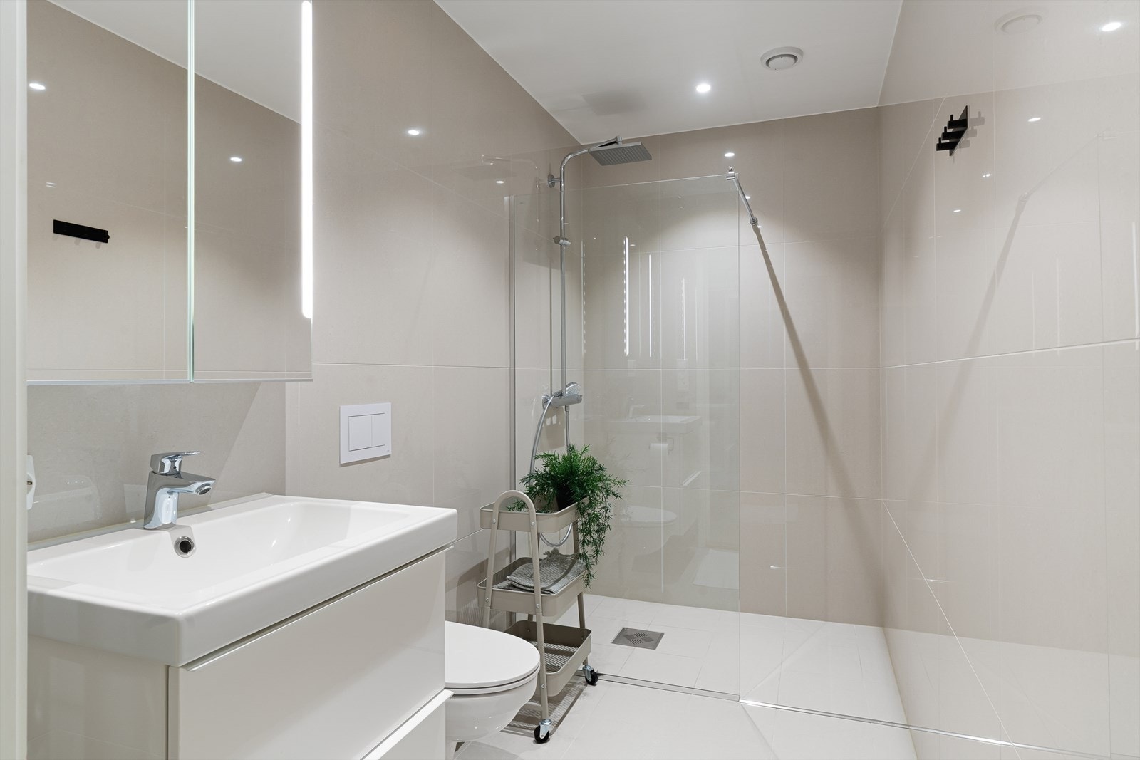 Praktisk ekstra helfliset bad, innredet med dusjhjørne, vegghengt wc og pen seksjon med vask Galleribilde