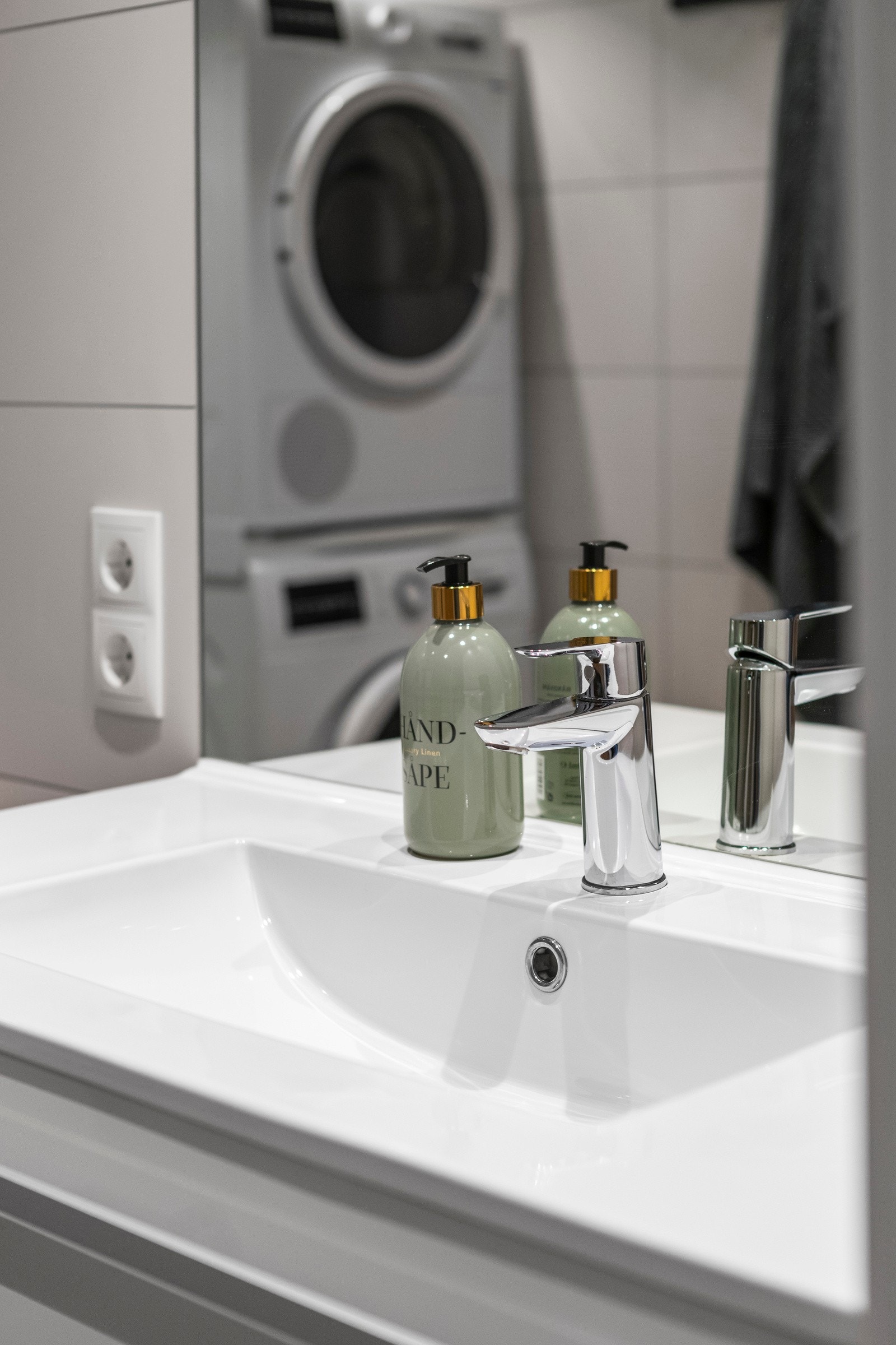 Innredningen består av en heldekkende servant på hvit skuffeseksjon, fastfliset speil, et veggmontert toalett og et dusjhjørne med innfellbare glassdører. Galleribilde