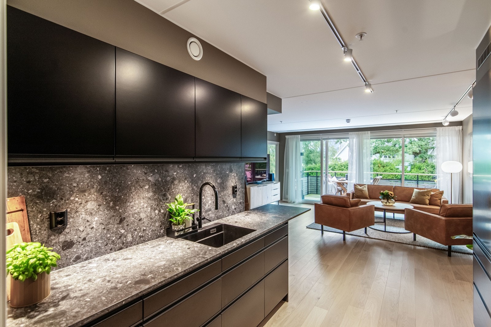 Kjøkkenet er plassert i åpen løsning med stuen, men tilbaketrukket i en tydelig definert sone. Galleribilde