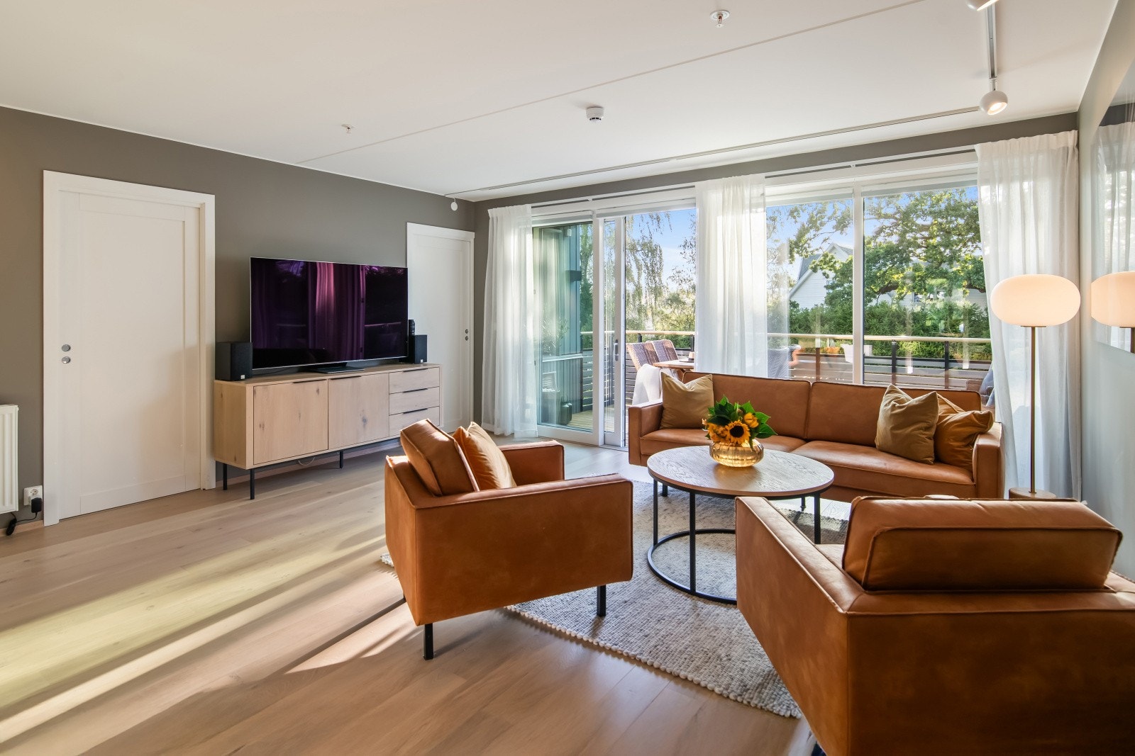 Stuen får rikelig med dagslys fra høye vinduer og skyvedører mot balkongen i vest, og den solrike uteplassen er en betydelig forlengelse av rommet i sommerhalvåret. Galleribilde