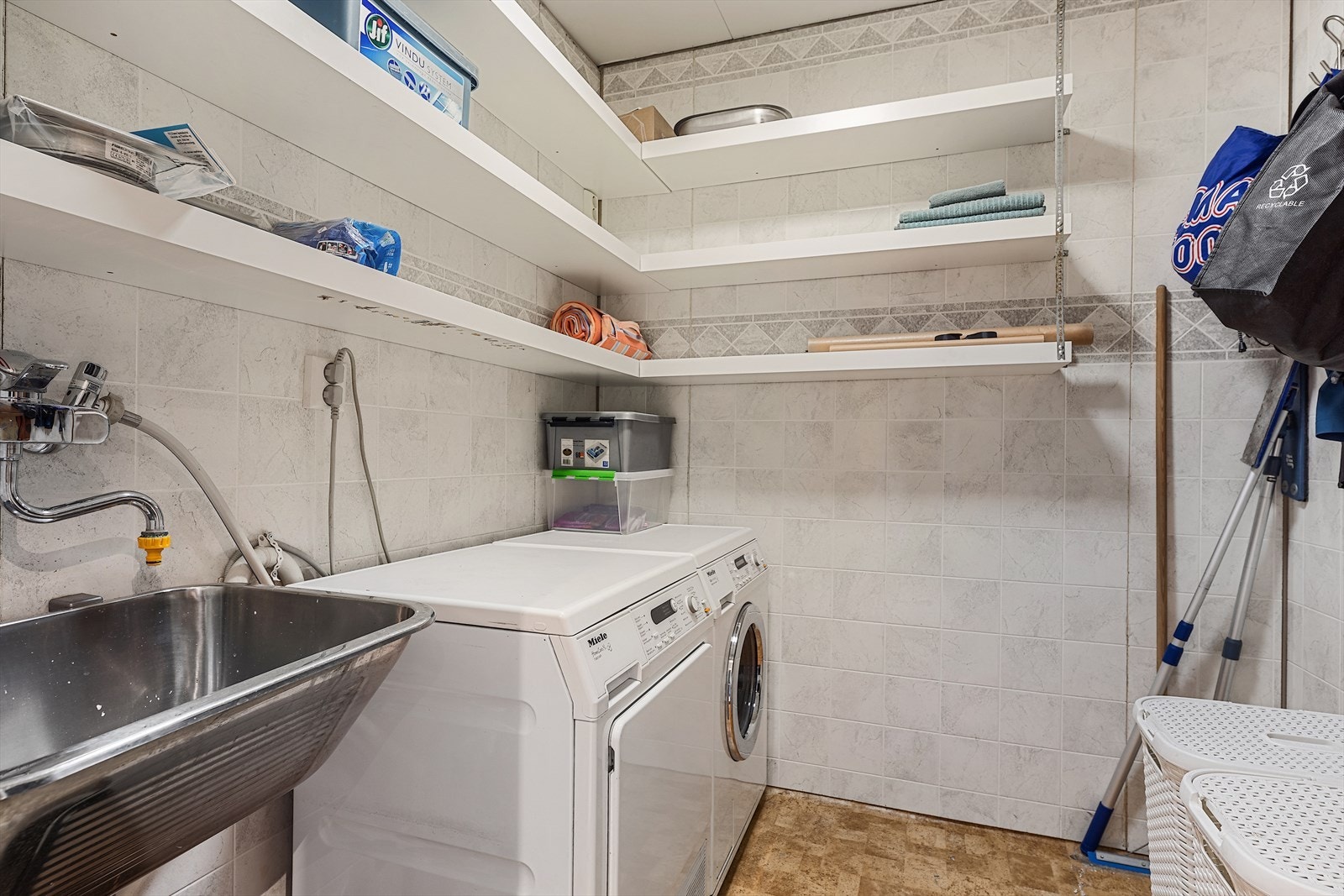 Praktisk og separat vaskerom med opplegg for vaskemaskin og tørketrommel. Det er belegg på gulv, og våtromsplater på vegger Galleribilde