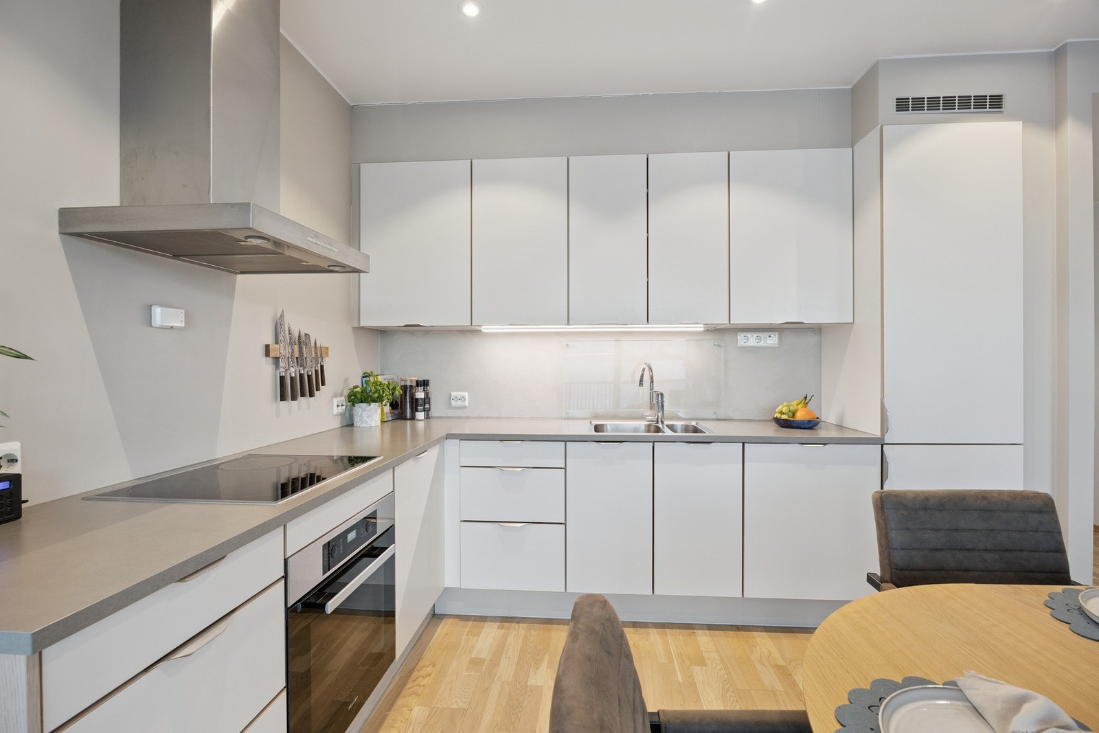 Kjøkkenet har innredning med glatte fronter og laminert benkeplate Galleribilde