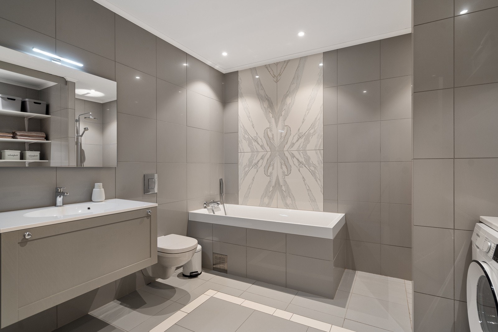 Smakfullt bad som er flislagt på gulv og vegger Galleribilde