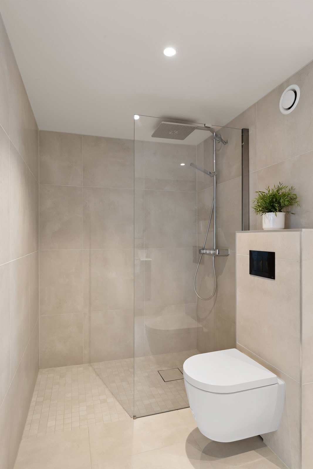 Badet er innredet med romslig dusjhjørne, vegghengt wc, pen seksjon med vask og opplegg for vaskemaskin Galleribilde